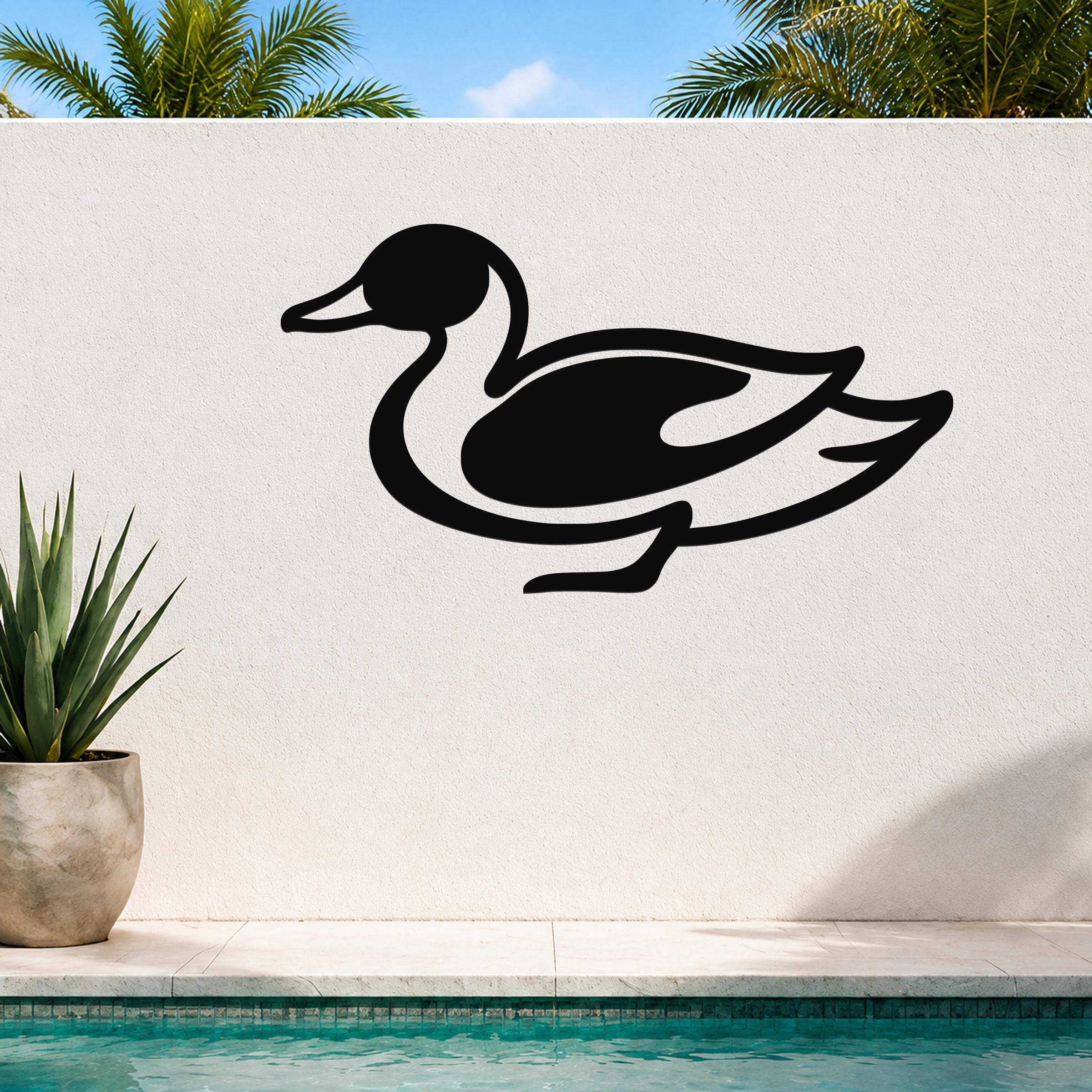 Black metal duck wall sculpture with a sleek silhouette, mounted on an outdoor wall beside a pool and potted plant.