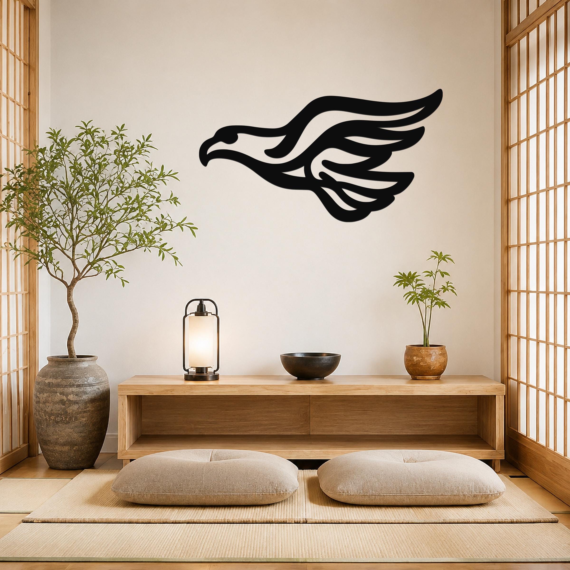 Black metal eagle wall art with flowing wing cutouts, mounted on a light-colored wall above a wooden console in a minimalist room.