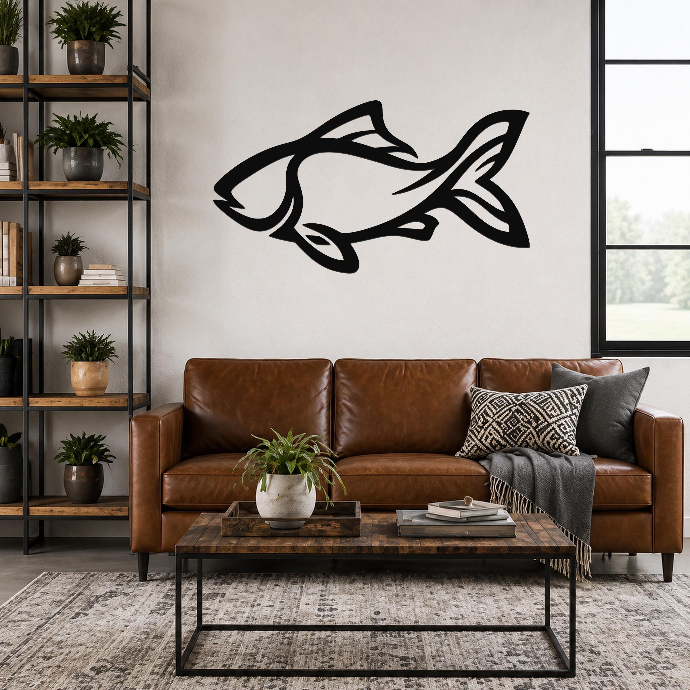 Black metal fish wall art with internal cutout details, mounted above a brown leather sofa in a living room.