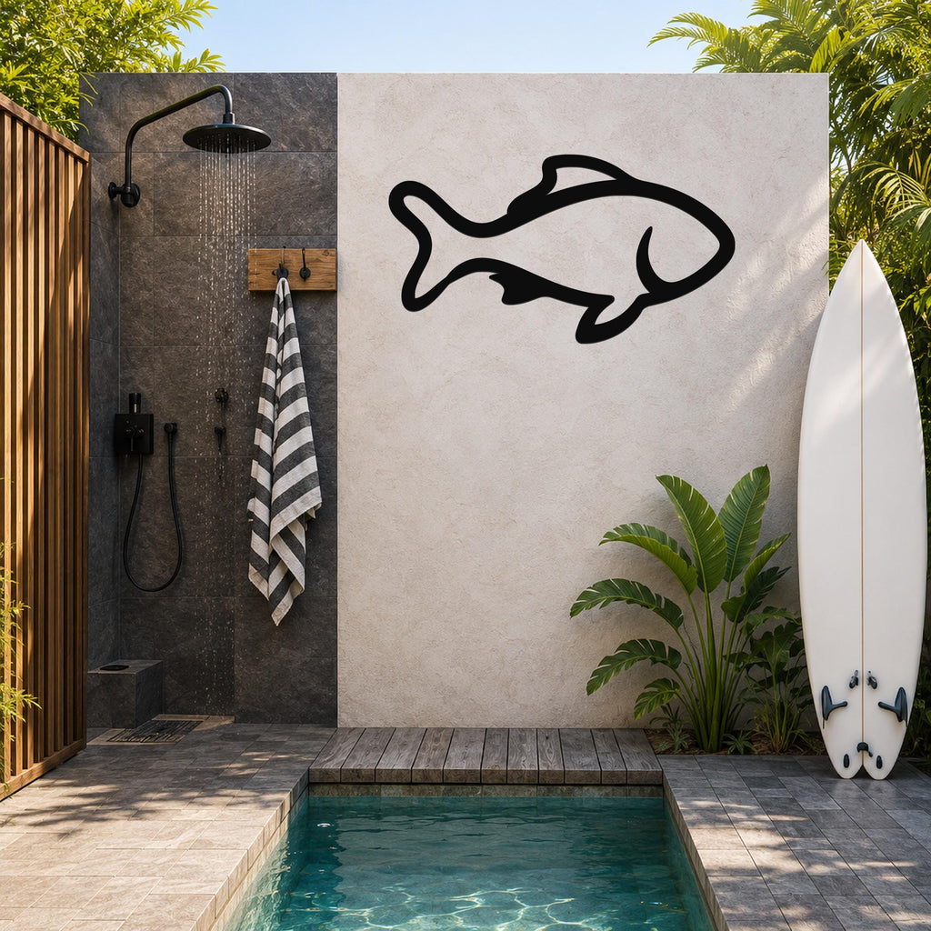 Black metal fish wall art with bold outline cutout, mounted on a light-colored outdoor wall beside a shower and pool area.