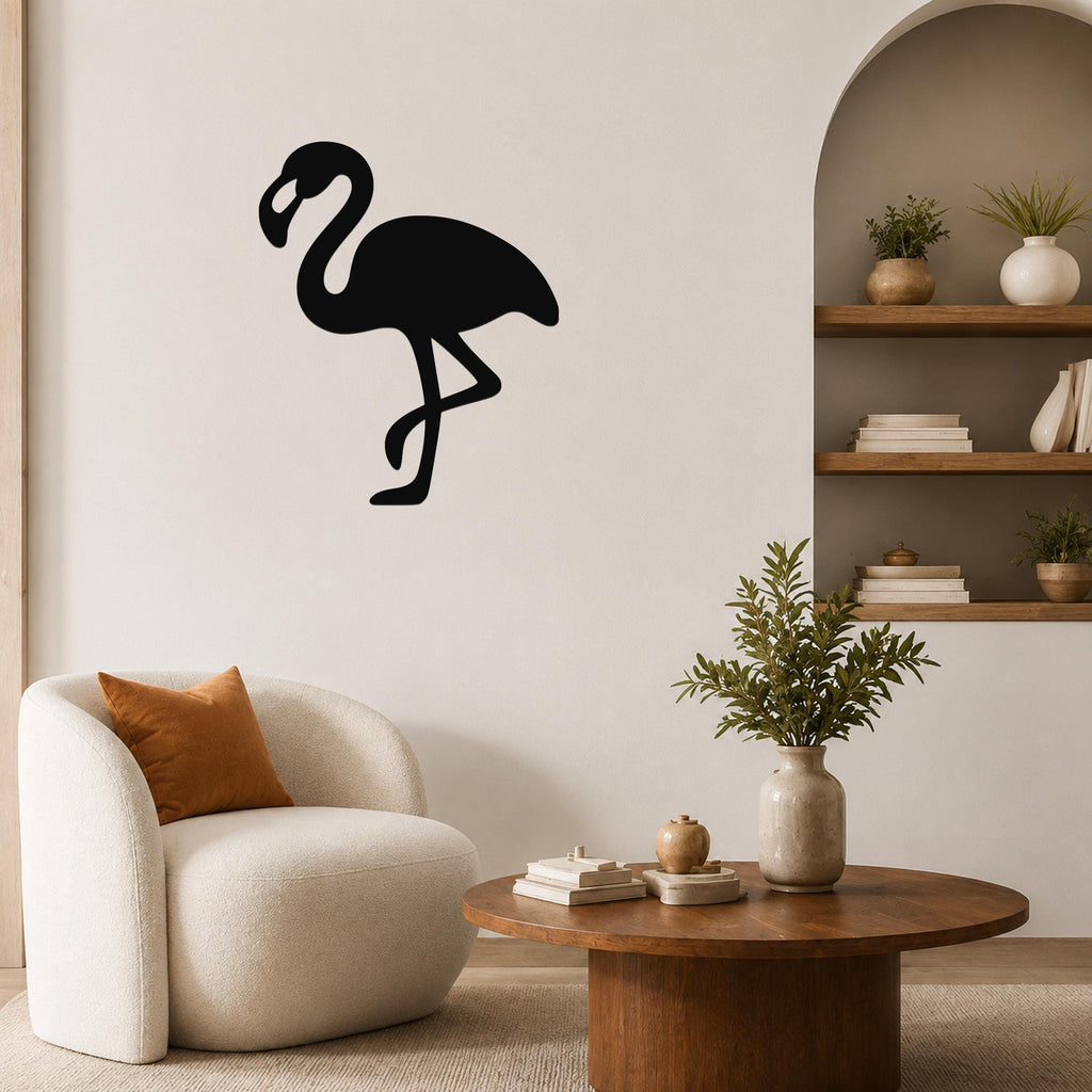 Black metal flamingo wall art silhouette mounted on a living room wall above a white armchair.