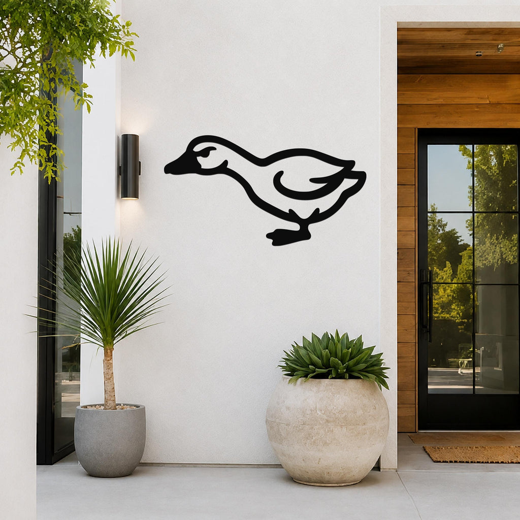 Black metal goose wall art silhouette mounted on a white exterior wall beside a glass door and potted plants.