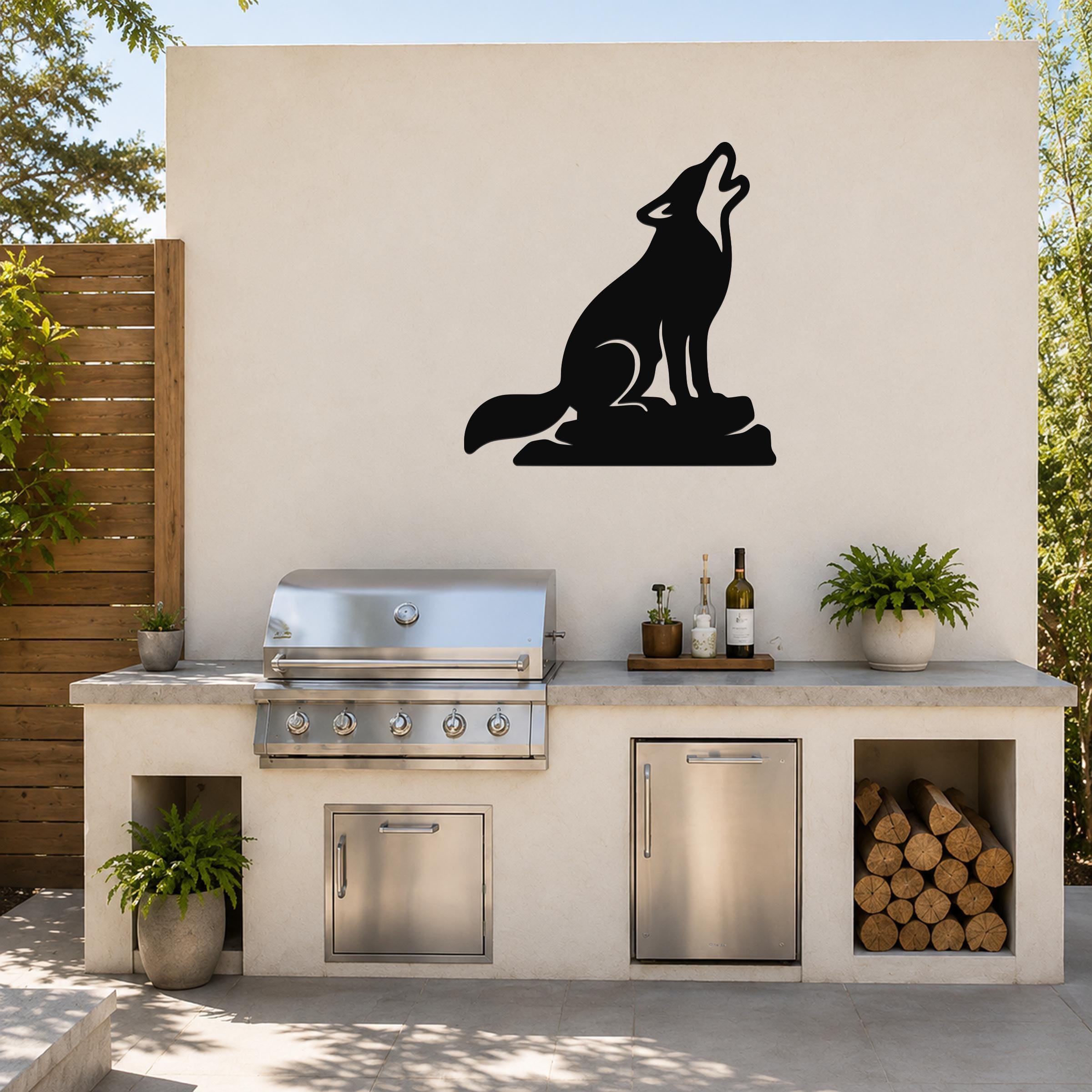 Black metal coyote wall art in a howling silhouette, mounted on an outdoor kitchen wall above a stainless steel grill and counter.