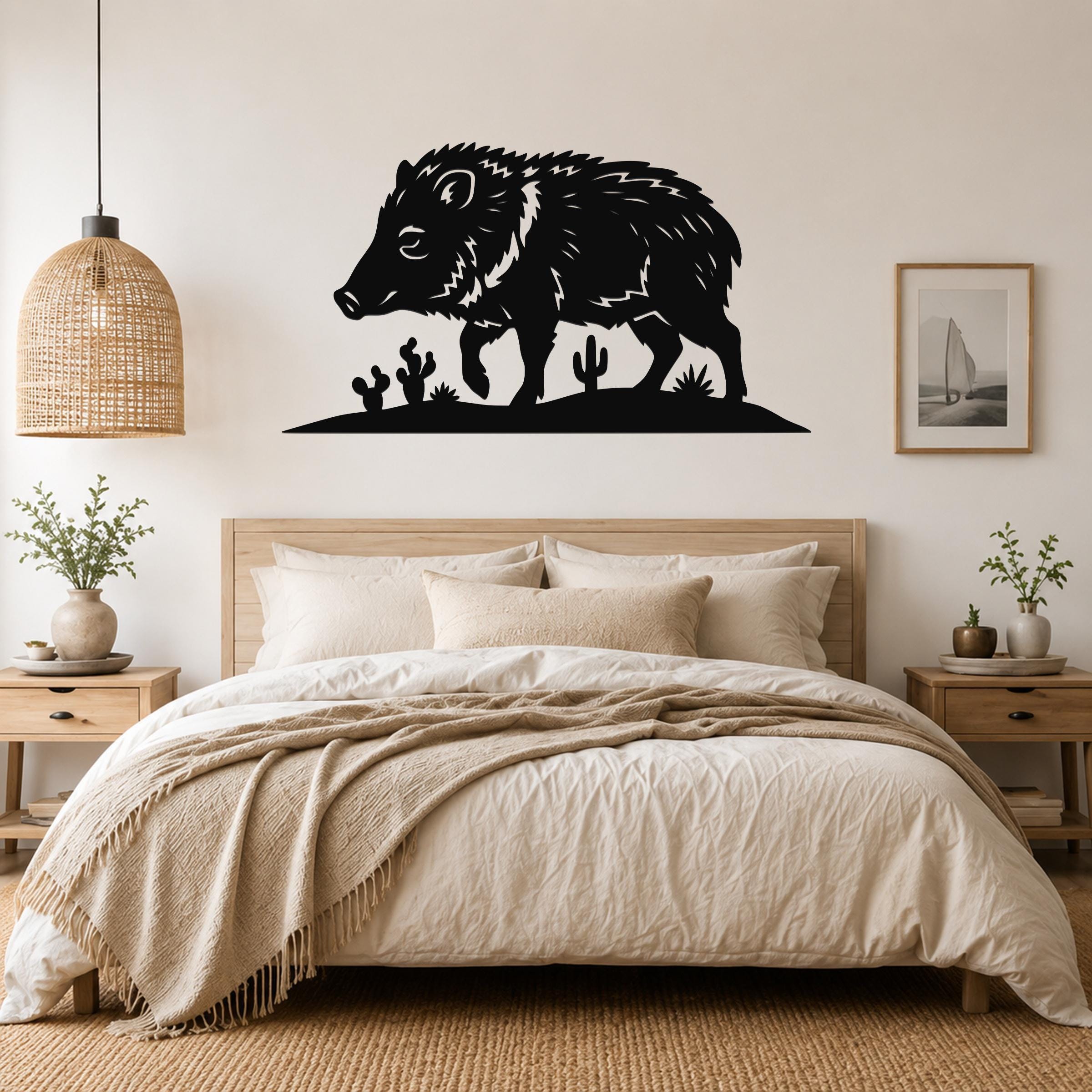 Black metal javelina wall art with cactus cutouts, mounted above a bed in a neutral bedroom.
