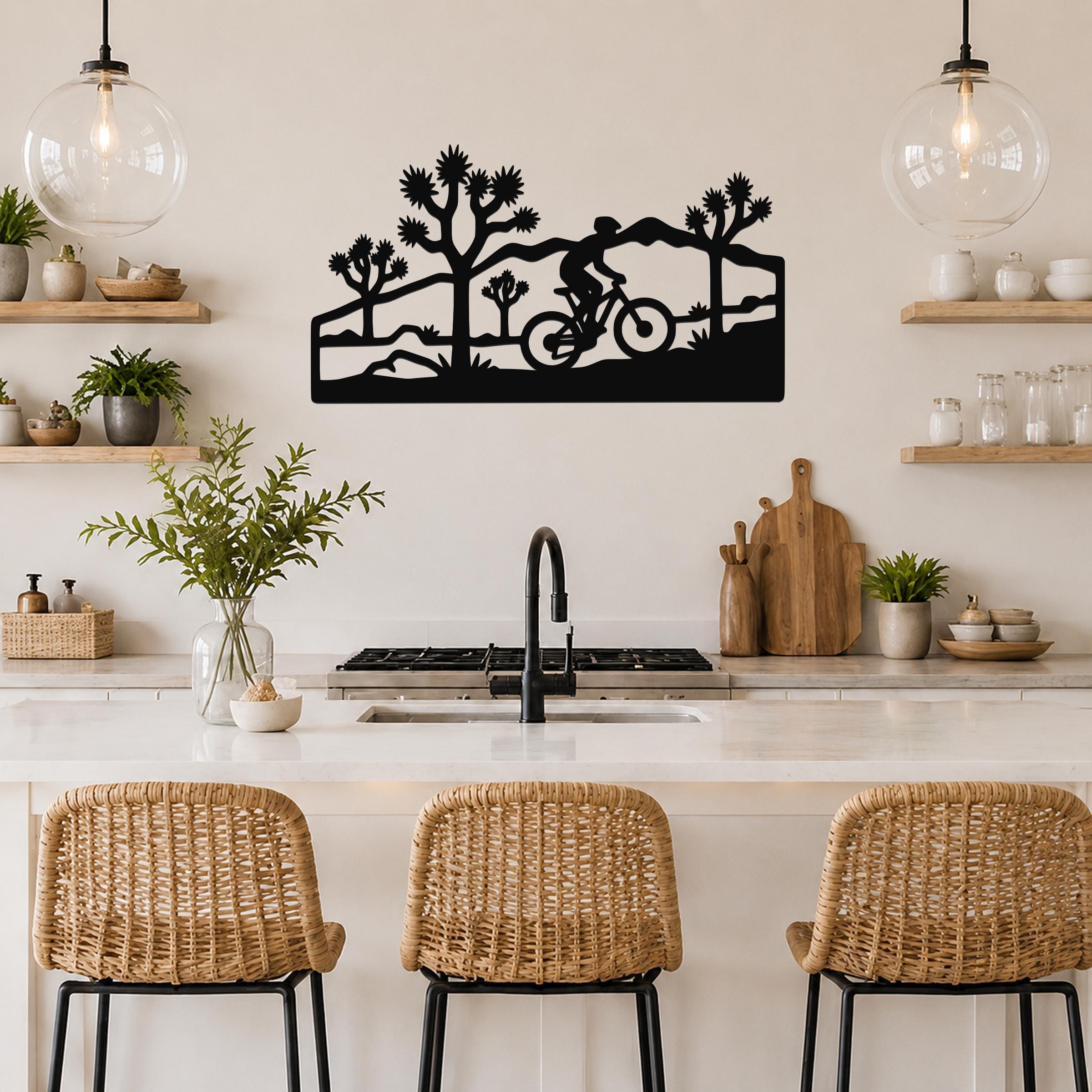 Black metal wall art with a silhouette of a cyclist and Joshua trees, mounted above a kitchen counter.