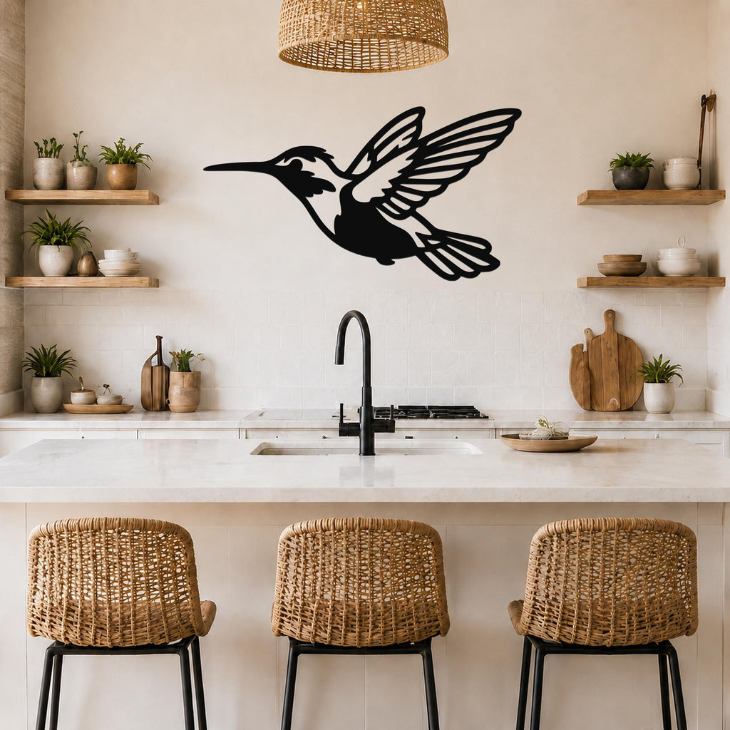 Black metal hummingbird wall art with open wings and internal cutout details, mounted on a kitchen wall above a counter.