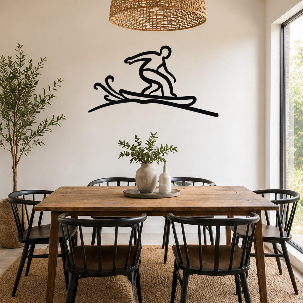 Black metal wall art silhouette of a snowboarder in motion, mounted on a white wall above a wooden dining table in a bright room.