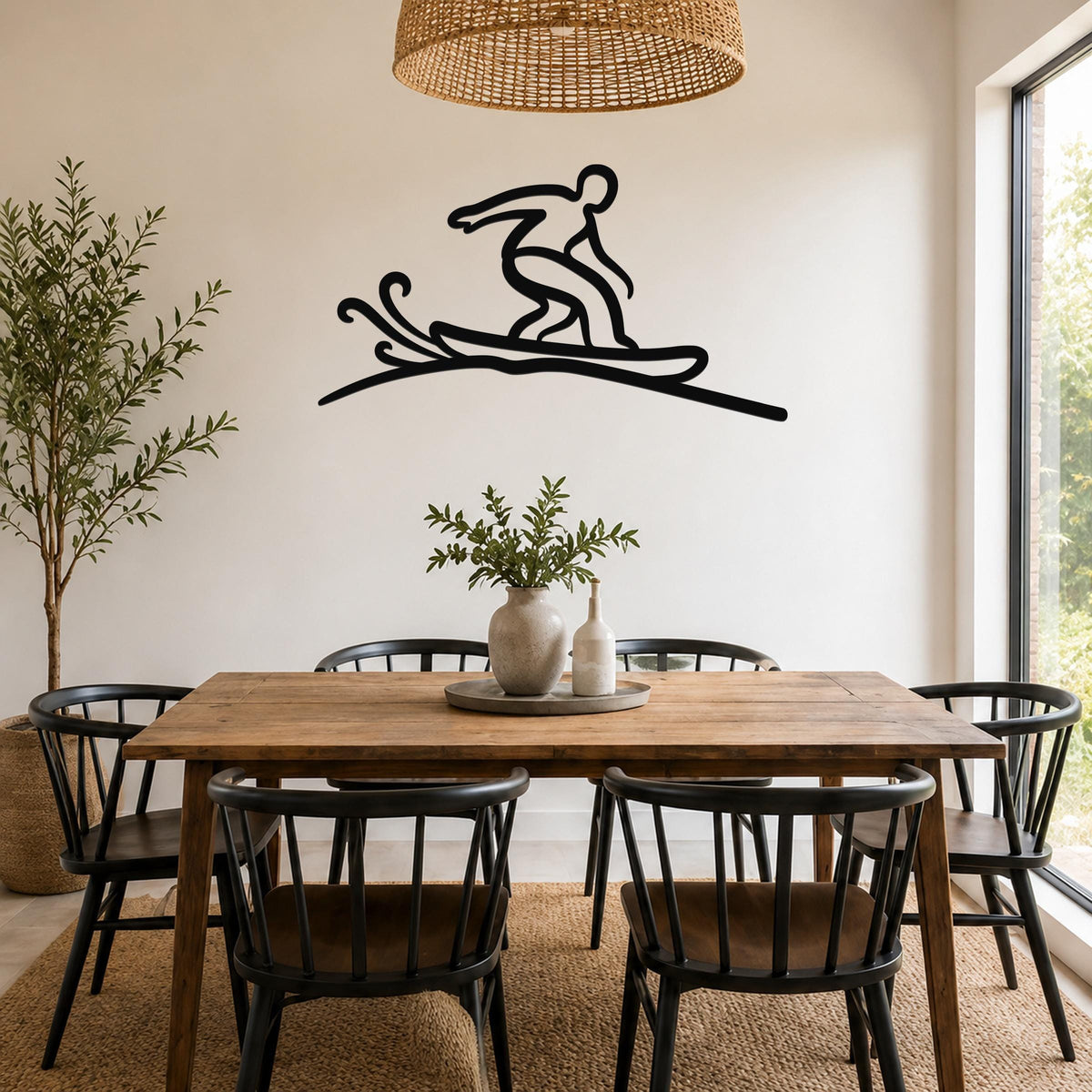 Black metal wall art silhouette of a snowboarder in motion, mounted on a white wall above a wooden dining table in a bright room.