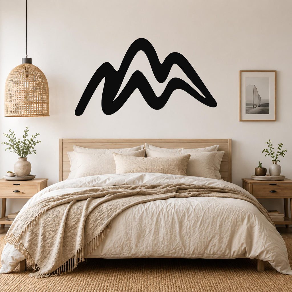 Black metal mountain silhouette wall art with flowing wave-like peaks, mounted above a wooden bed in a neutral bedroom.