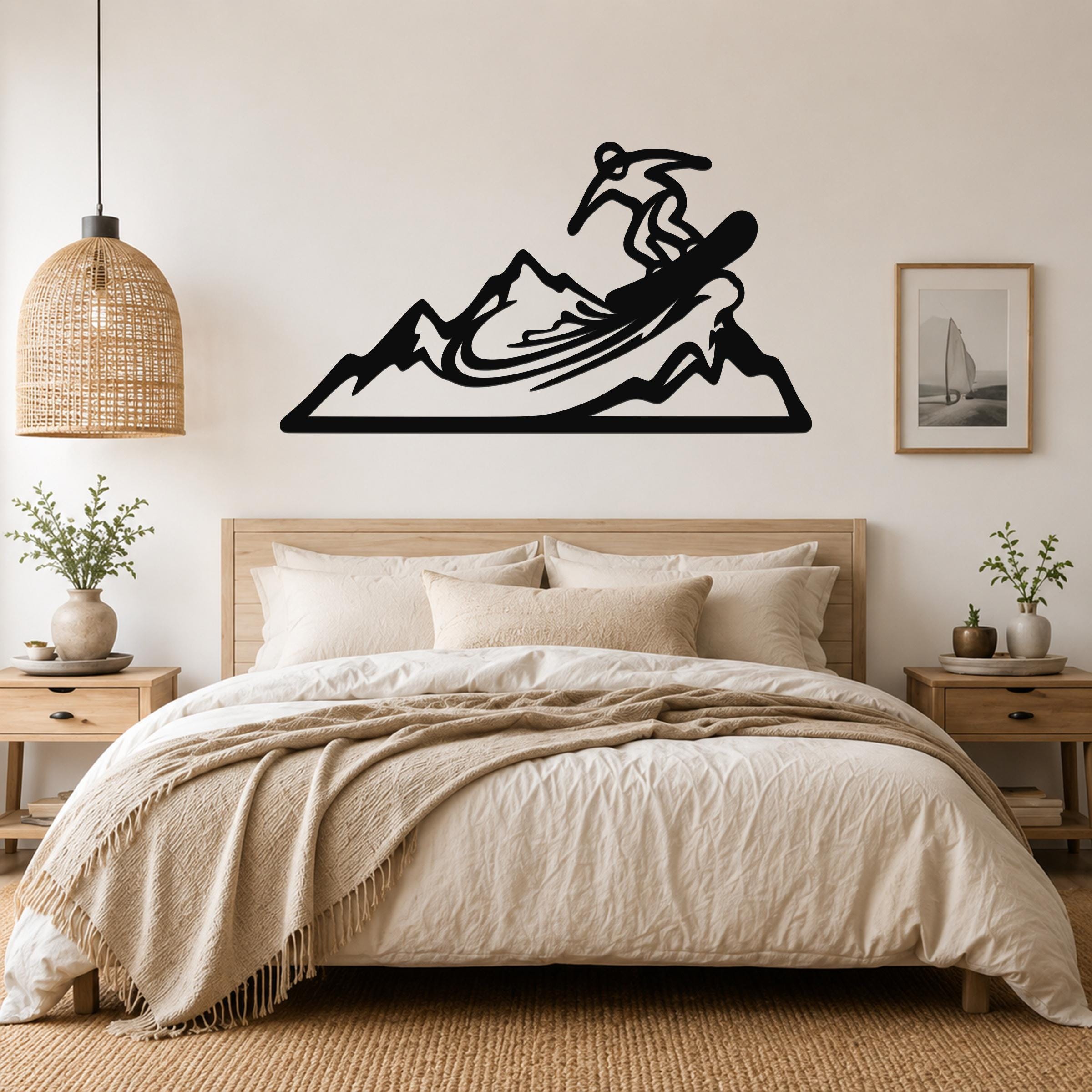 Black metal wall art cutout of a snowboarder on a mountain, mounted above a bed in a bedroom.