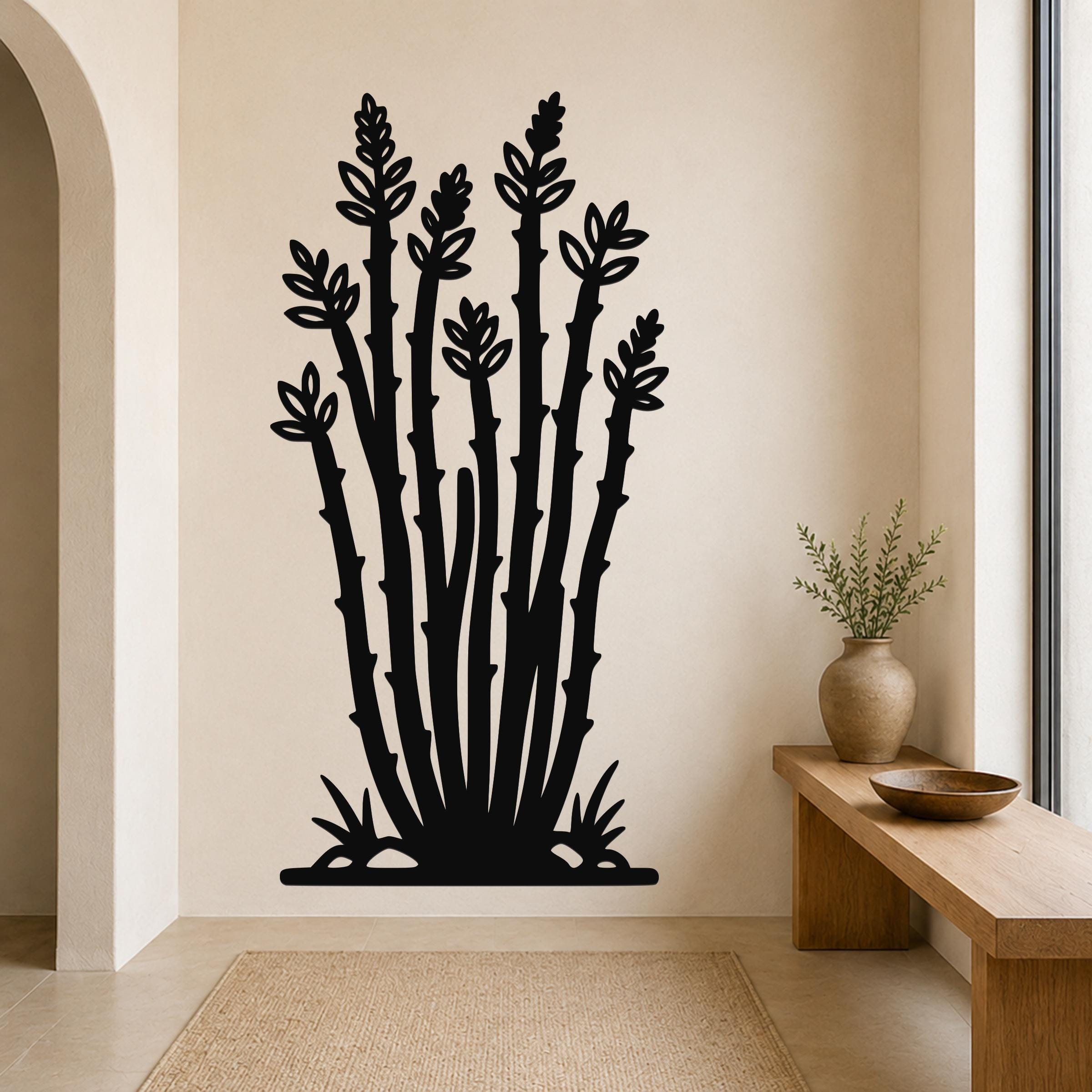 Black metal ocotillo wall art with leafy branch cutouts, mounted on a beige wall above a wooden bench in a minimalist entryway.