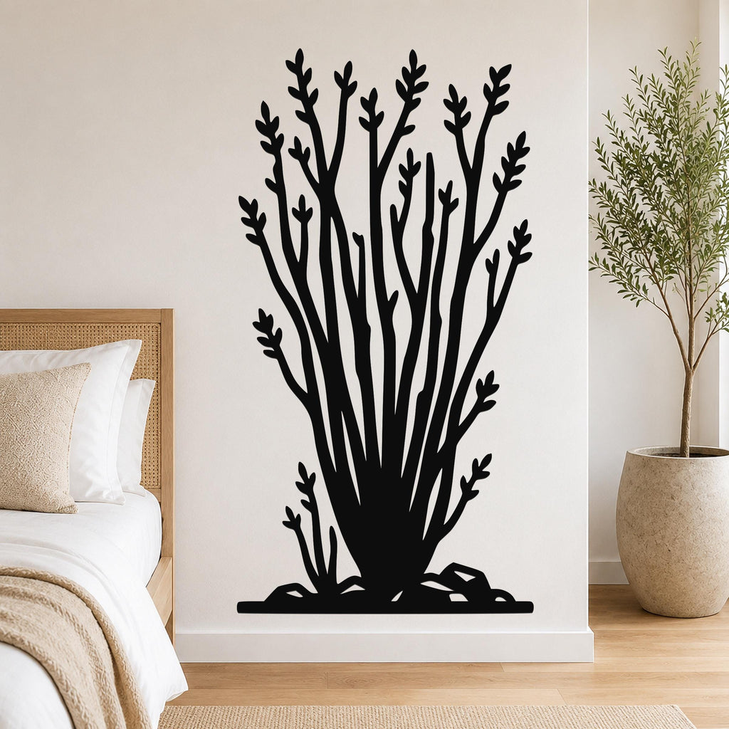 Black metal ocotillo wall art with branching silhouette and leaf cutouts, mounted on a bedroom wall above a bed.