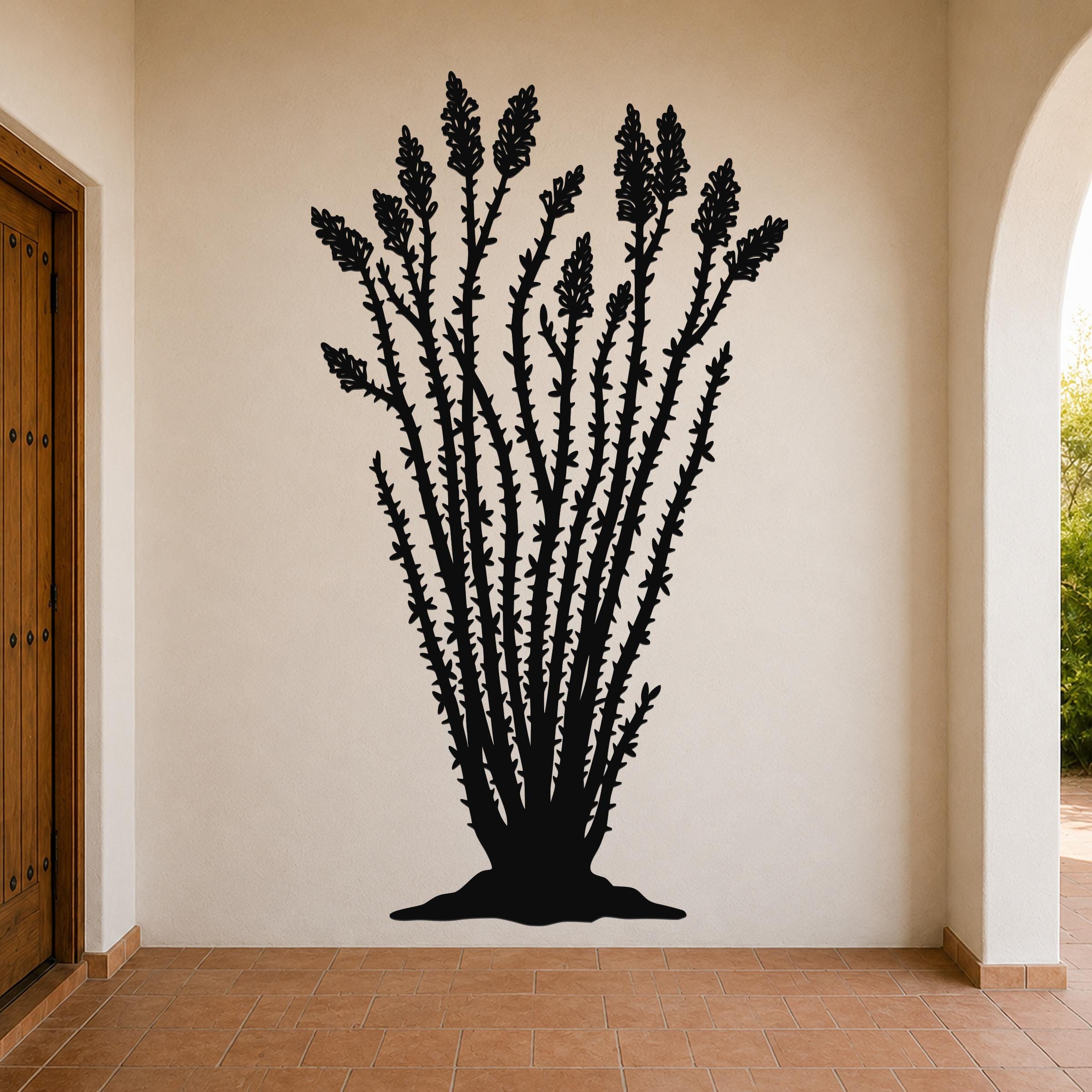 Black metal ocotillo wall art silhouette with spiny stems and tubular flower cutouts, mounted on a beige interior wall above terracotta tile flooring.