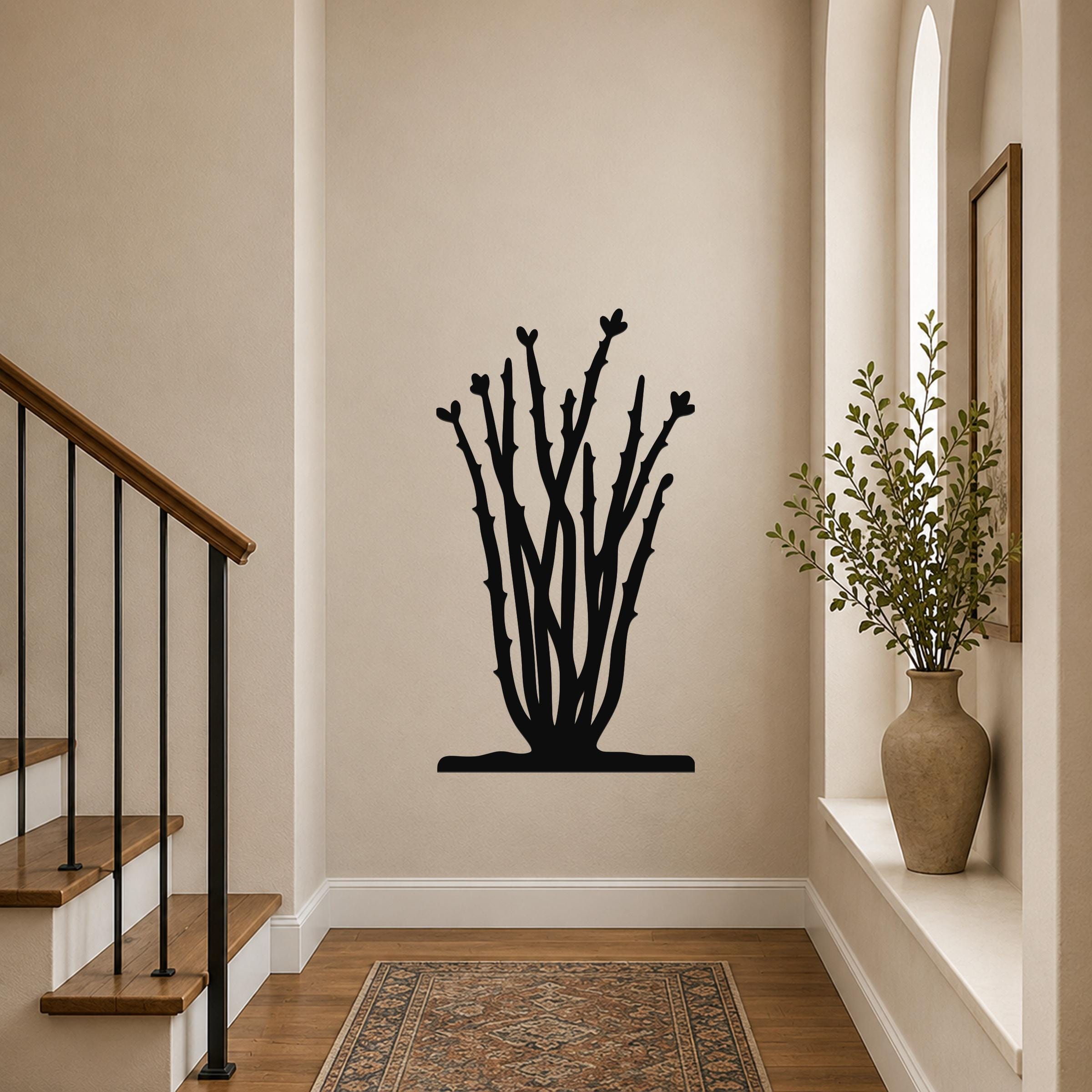 Black metal ocotillo wall art with branch and flower cutouts, mounted on a hallway wall above a patterned rug.