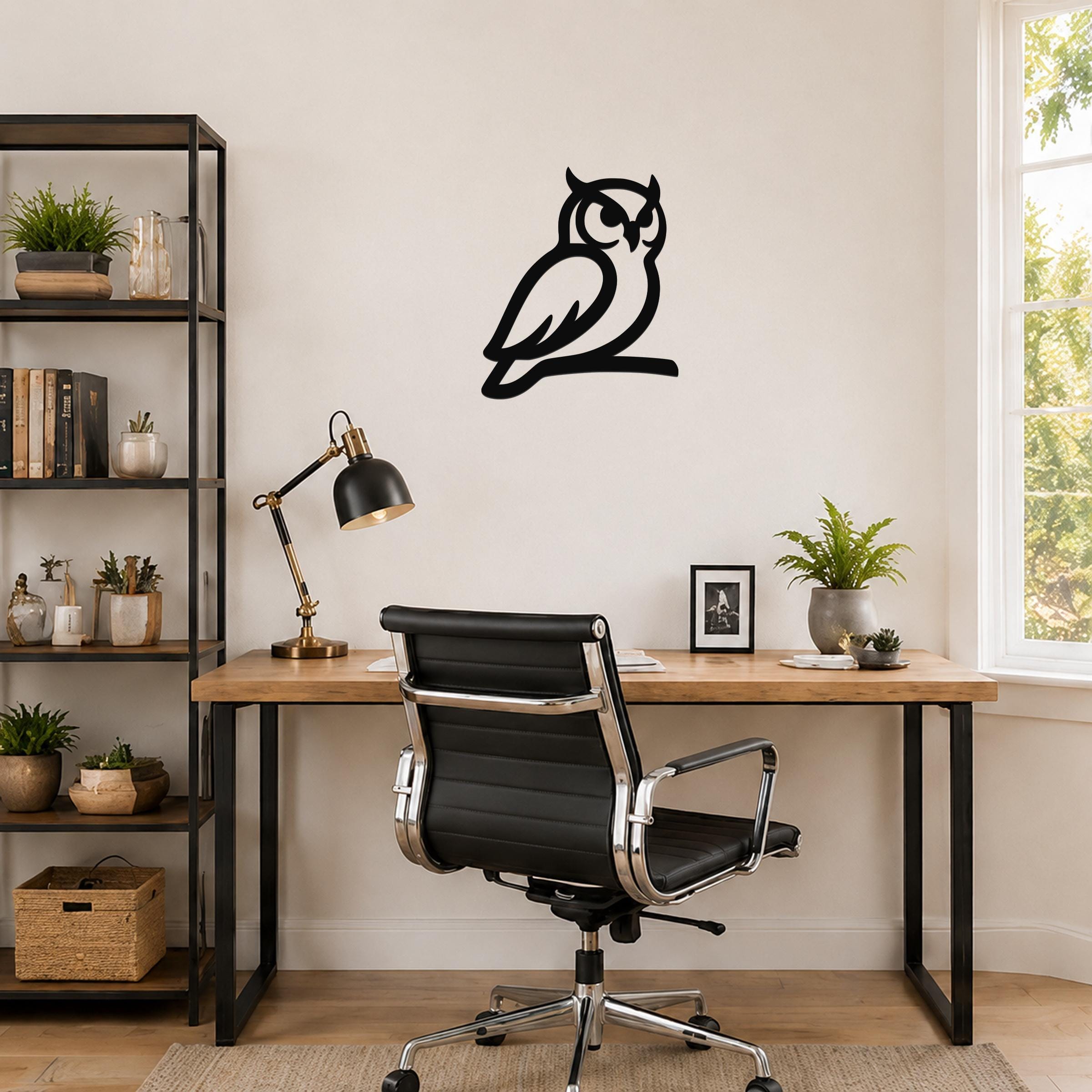 Black metal owl wall art in a silhouette style, mounted on a wall above a wooden desk in a home office.