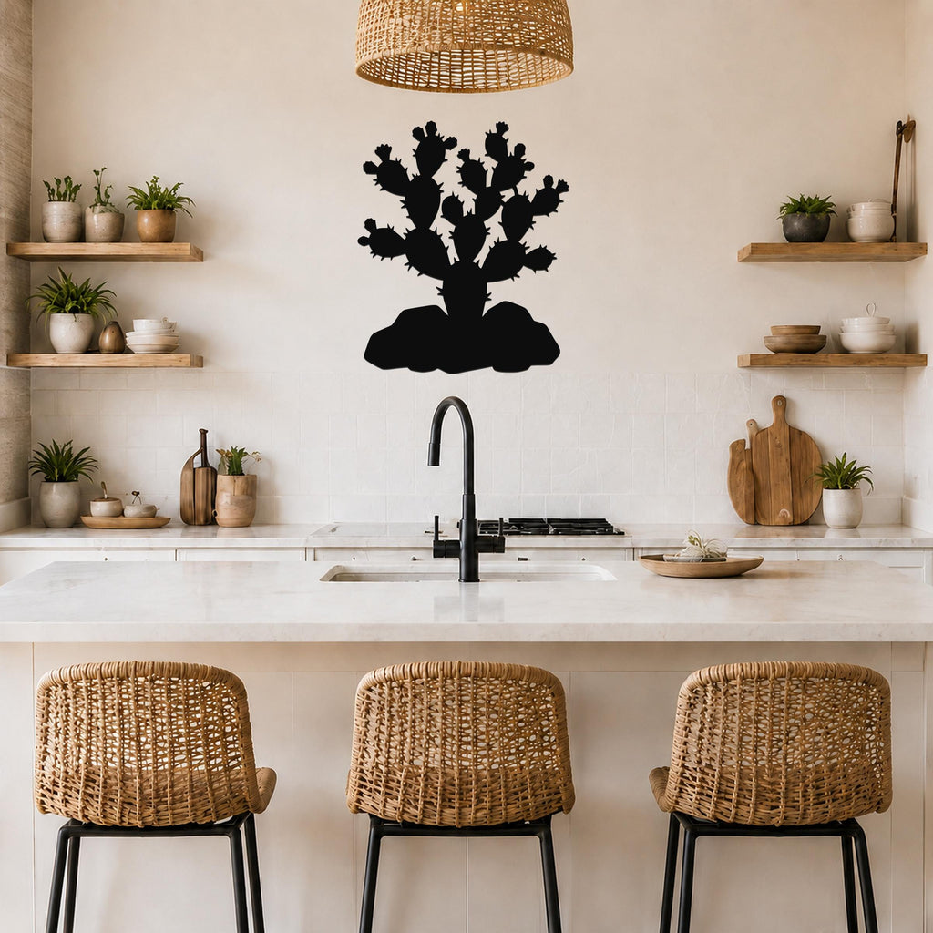 Black metal cactus wall art with a prickly pear silhouette, mounted on a kitchen wall above a counter with a sink and wicker bar stools.