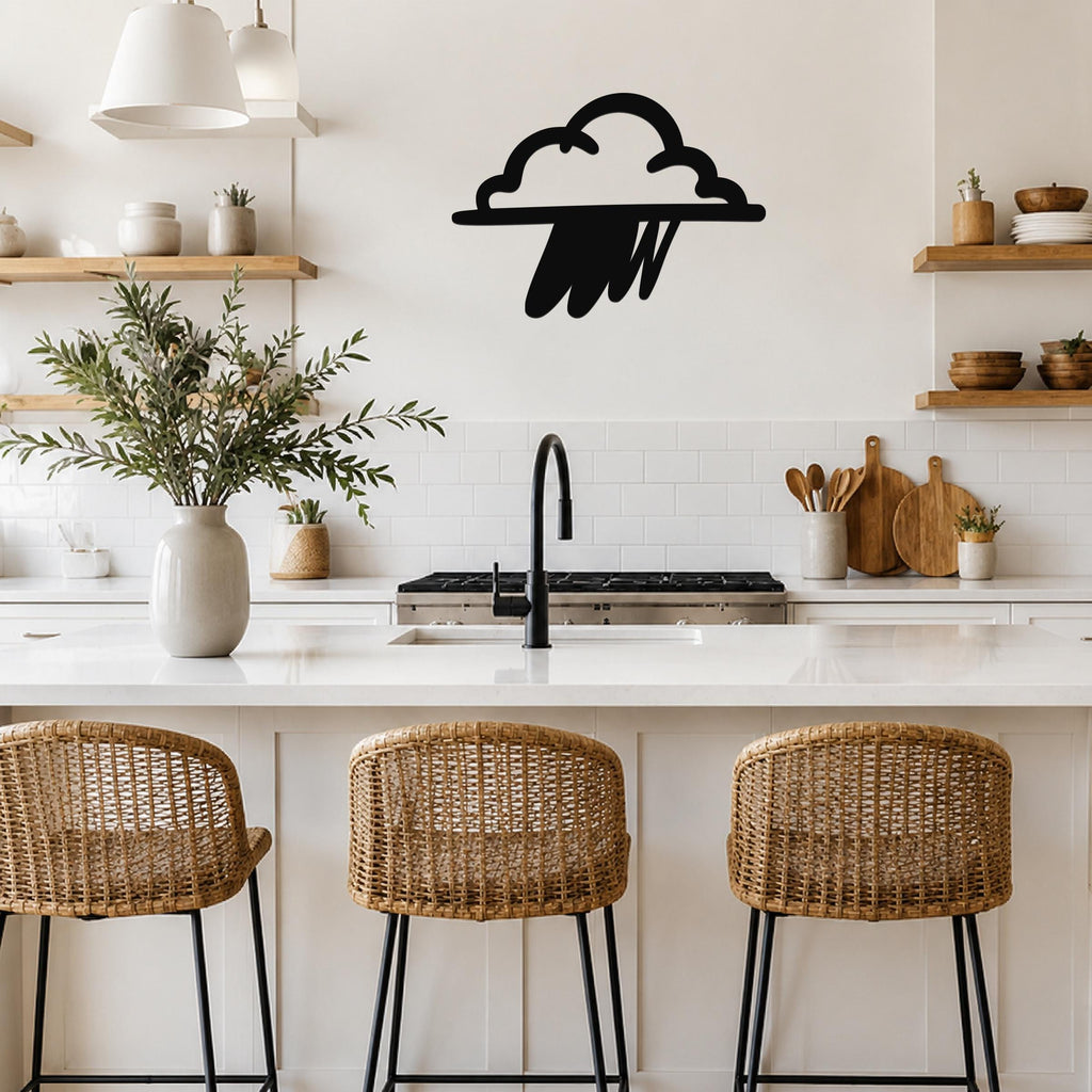 Black metal rain cloud wall art with raindrop cutouts, mounted on a kitchen wall above a white countertop.