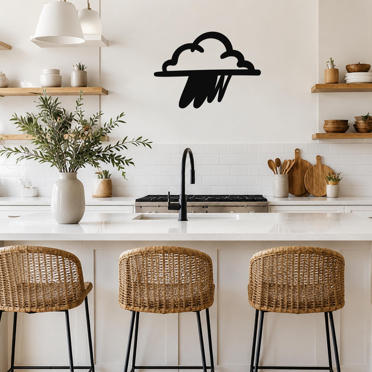 Black metal rain cloud wall art with raindrop cutouts, mounted on a kitchen wall above a white countertop.
