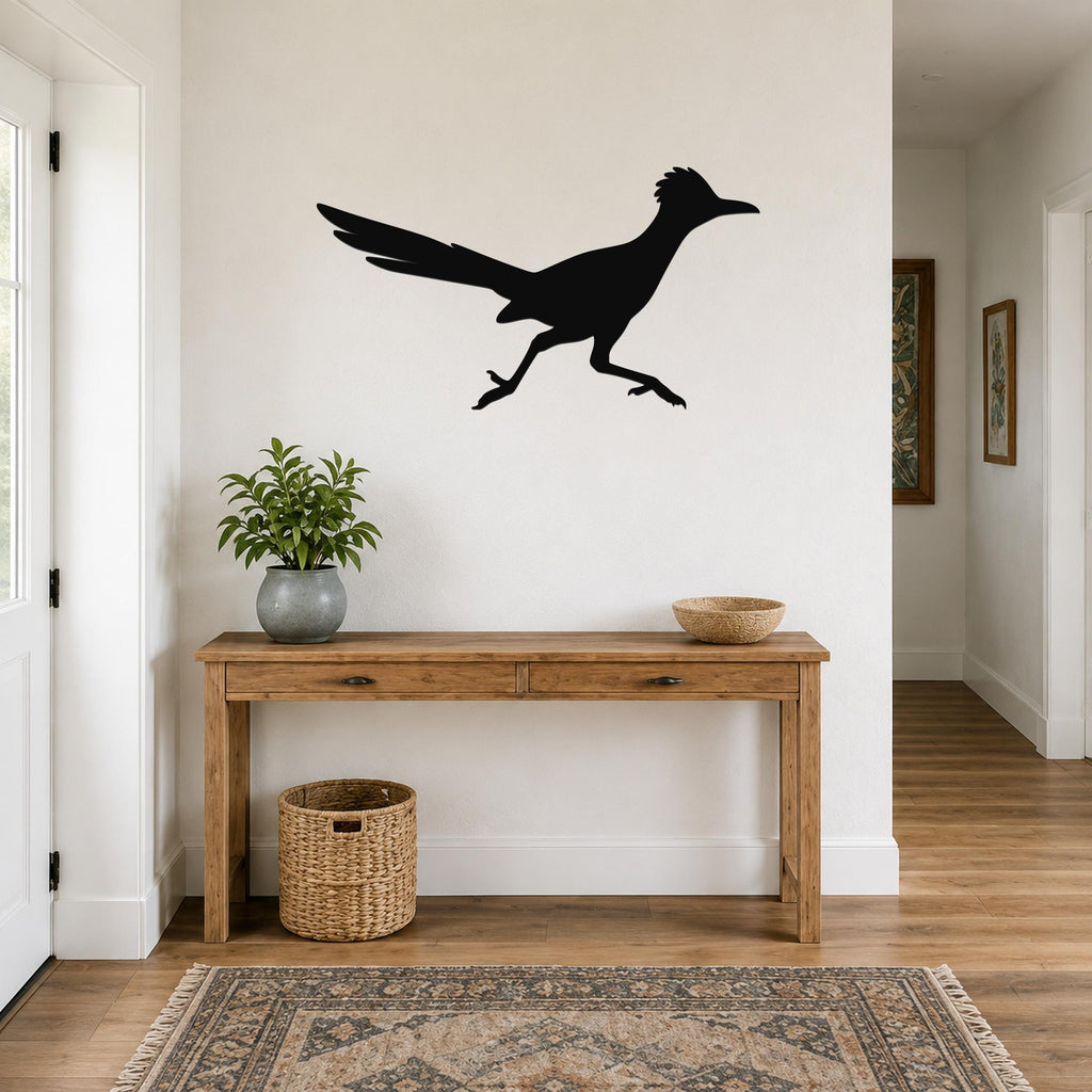 Black metal roadrunner wall art silhouette mounted above a wooden console table in a bright entryway.
