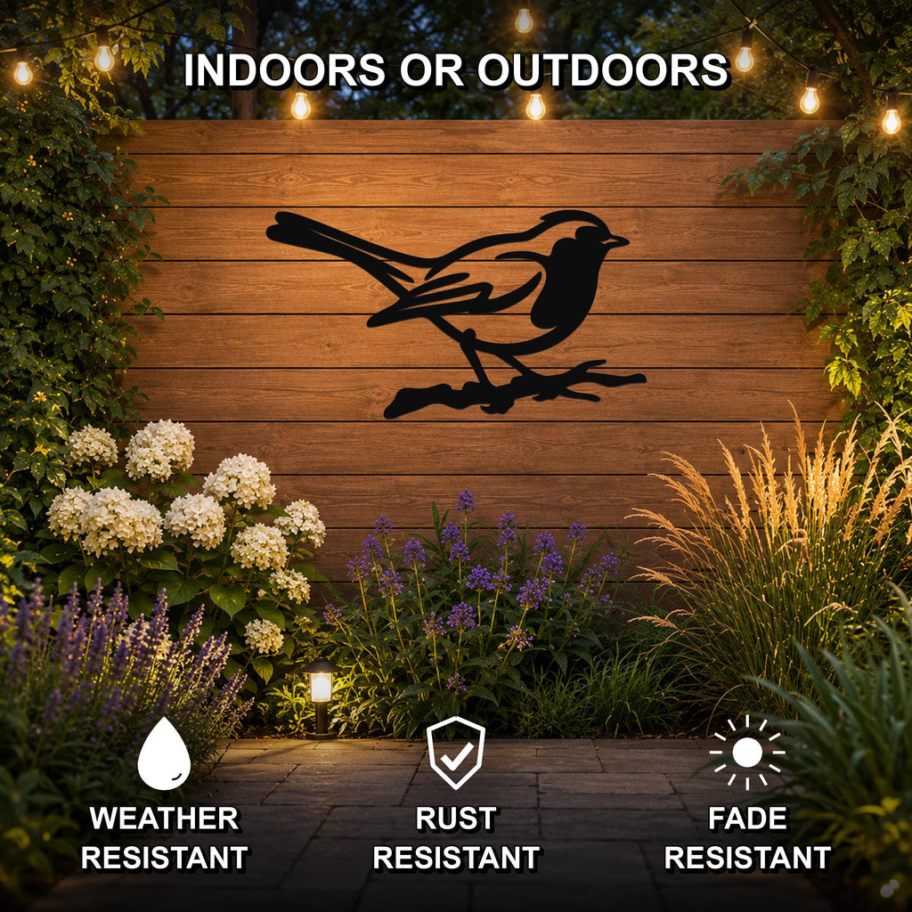 Black metal robin wall art silhouette perched on a branch, mounted on a wooden outdoor wall with string lights and garden plants, weather resistant, rust resistant, and fade resistant.