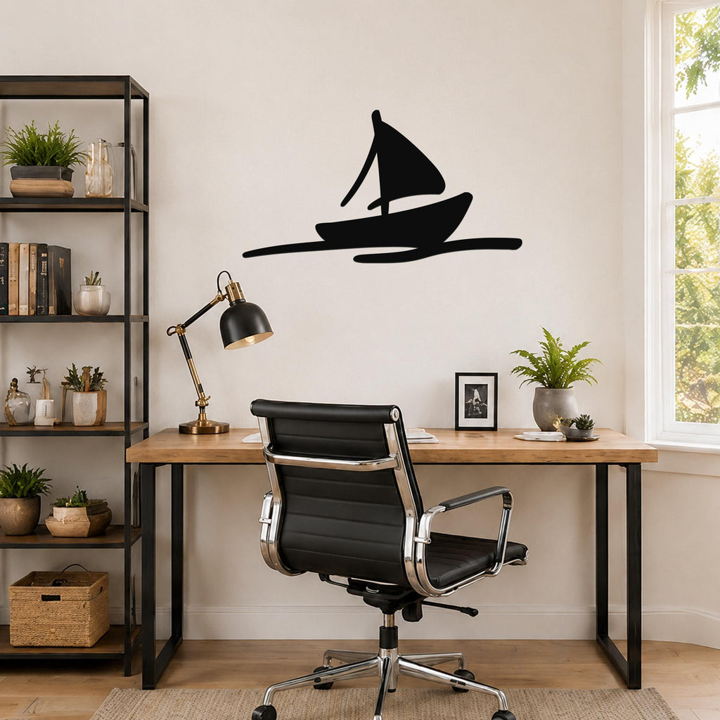 Black metal sailboat wall art with a wave cutout, mounted on a wall above a wooden desk in a home office.