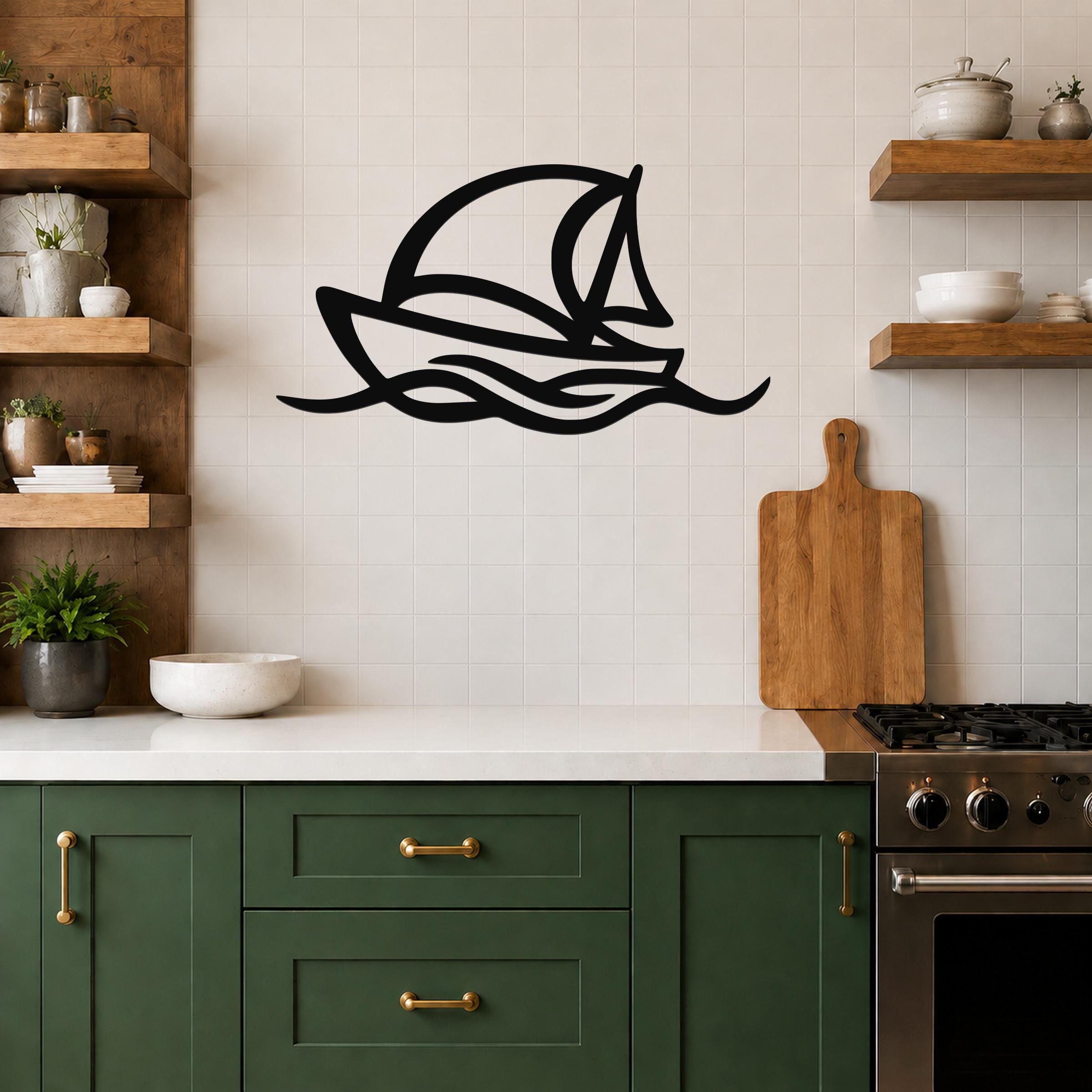 Black metal sailboat wall art with wave cutouts, mounted on a tiled kitchen wall above a counter.