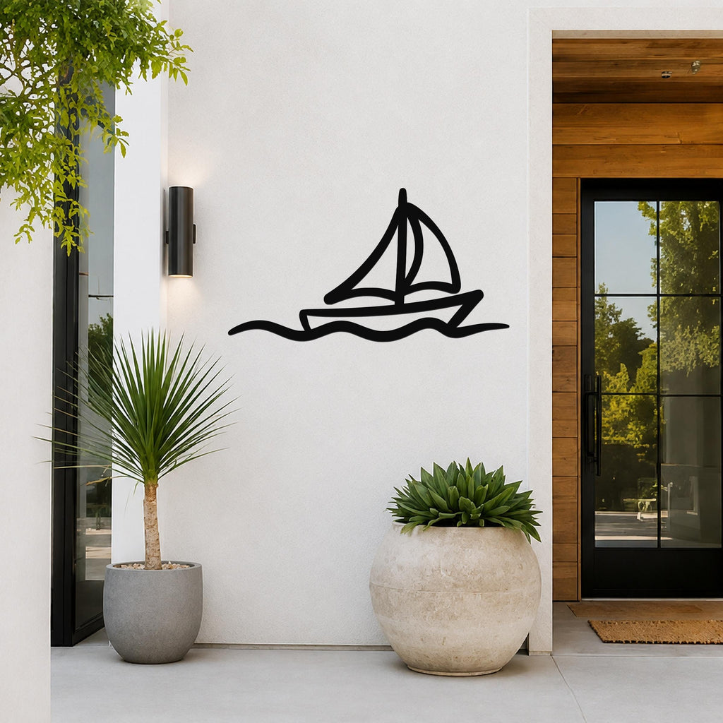Black metal sailboat wall art with wavy line cutout, mounted on a white exterior wall beside a glass door and potted plants.
