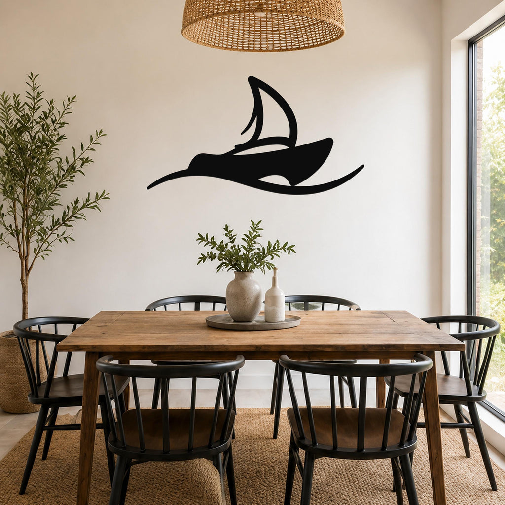 Black metal sailboat wall art with a silhouette design, mounted on a white wall above a wooden dining table in a bright dining room.