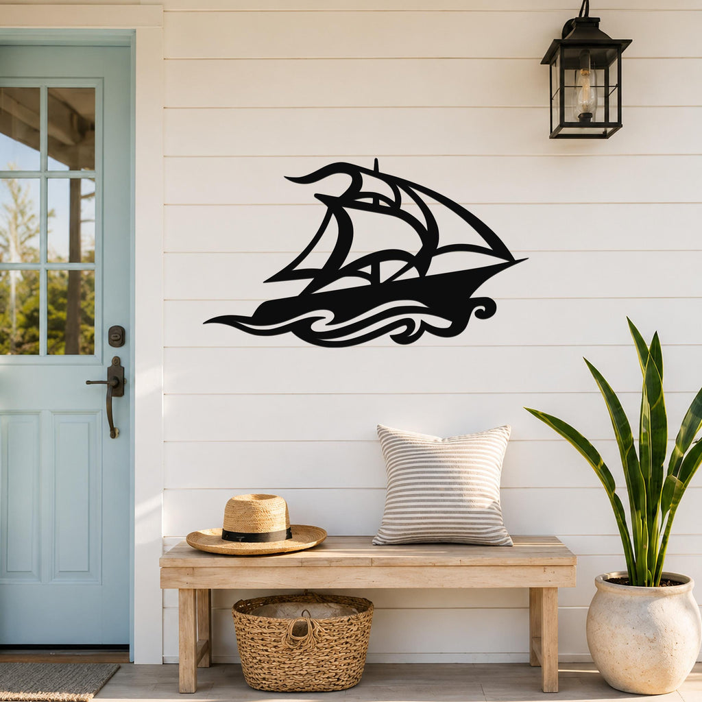 Black metal sailboat wall art with wave cutouts, mounted on a white shiplap wall above a wooden bench in a coastal entryway.
