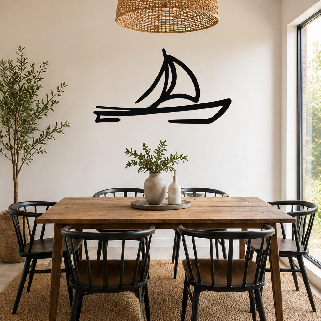 Black metal sailboat wall art silhouette mounted on a white wall above a wooden dining table in a bright dining room.
