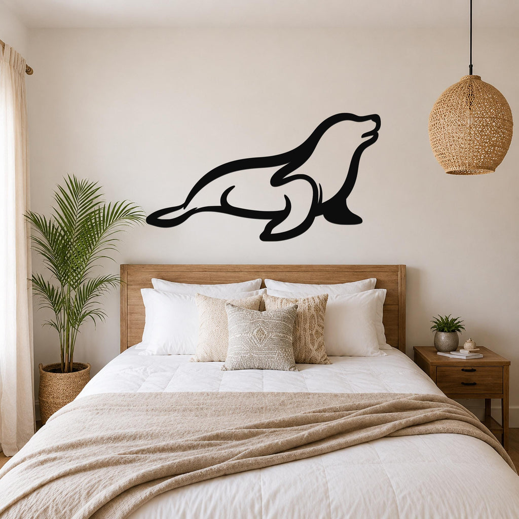 Black metal sea lion wall art in a silhouette style, mounted above a wooden bed in a neutral bedroom.