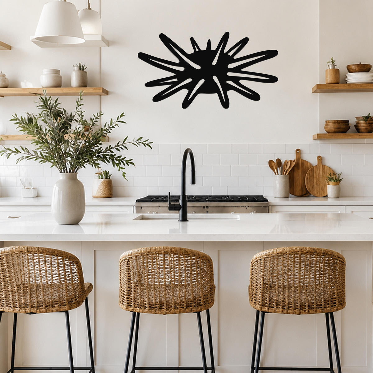 Black metal sea urchin wall art with spiky cutout design, mounted on a kitchen wall above a white countertop.