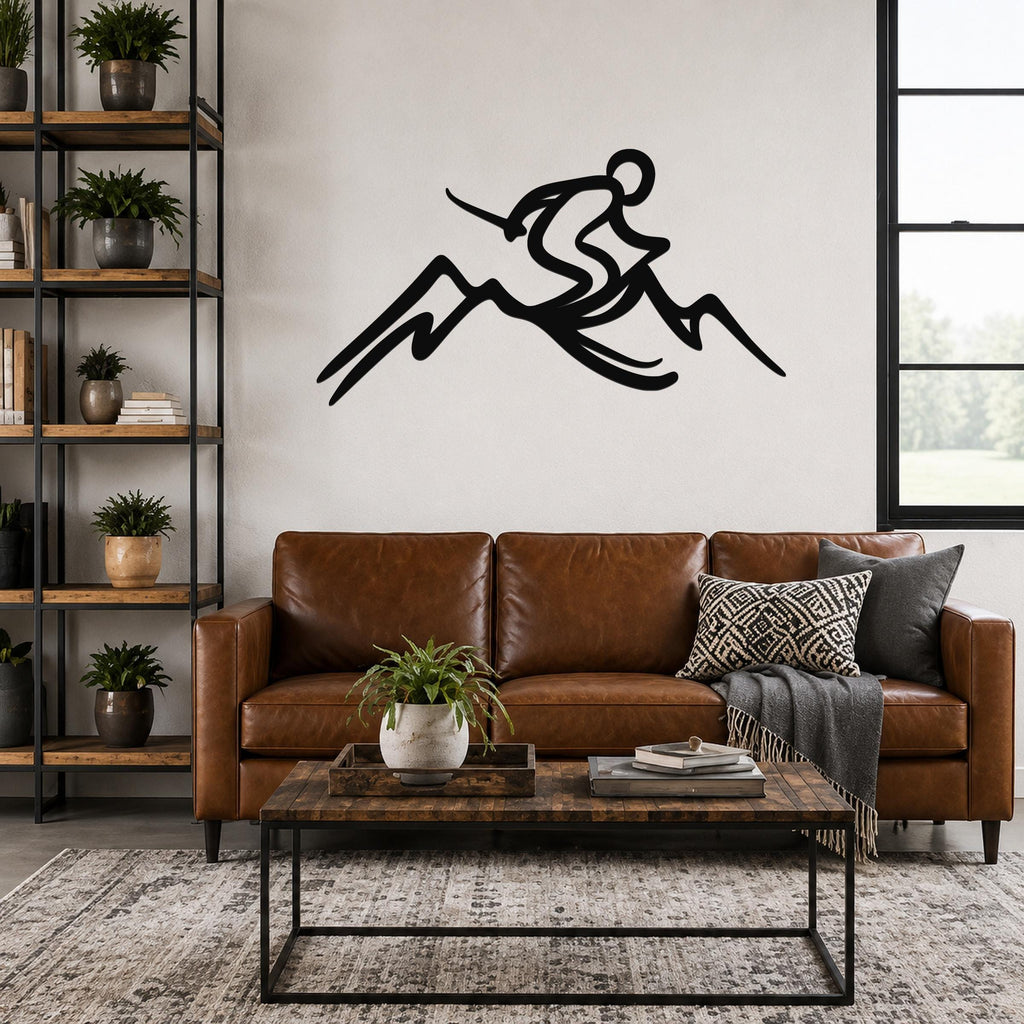 Black metal wall sculpture of a skier in motion above a mountain, mounted on a living room wall above a brown leather sofa.