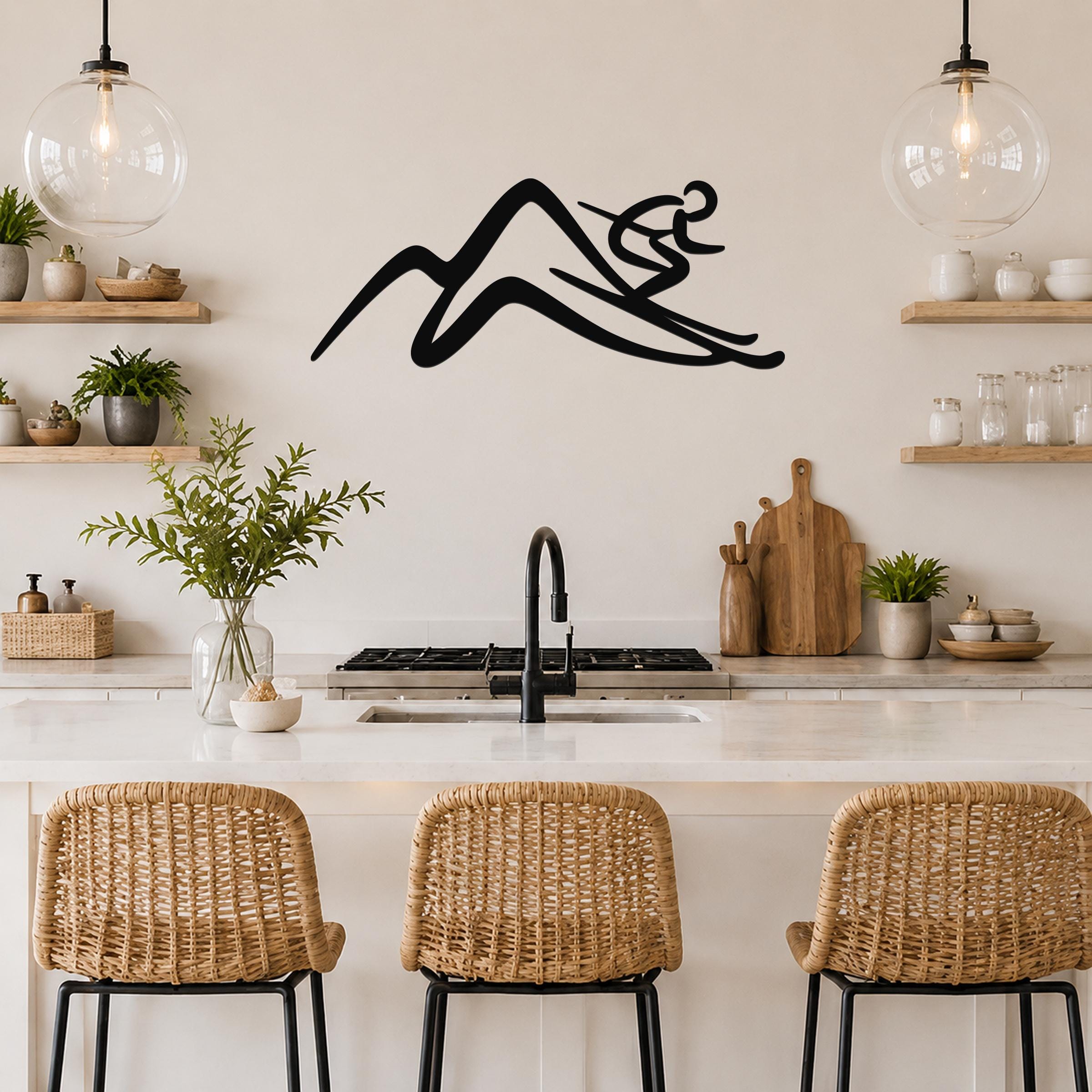 Black metal wall art featuring a skier silhouette above a mountain, mounted on a kitchen wall above a counter with wicker bar stools.