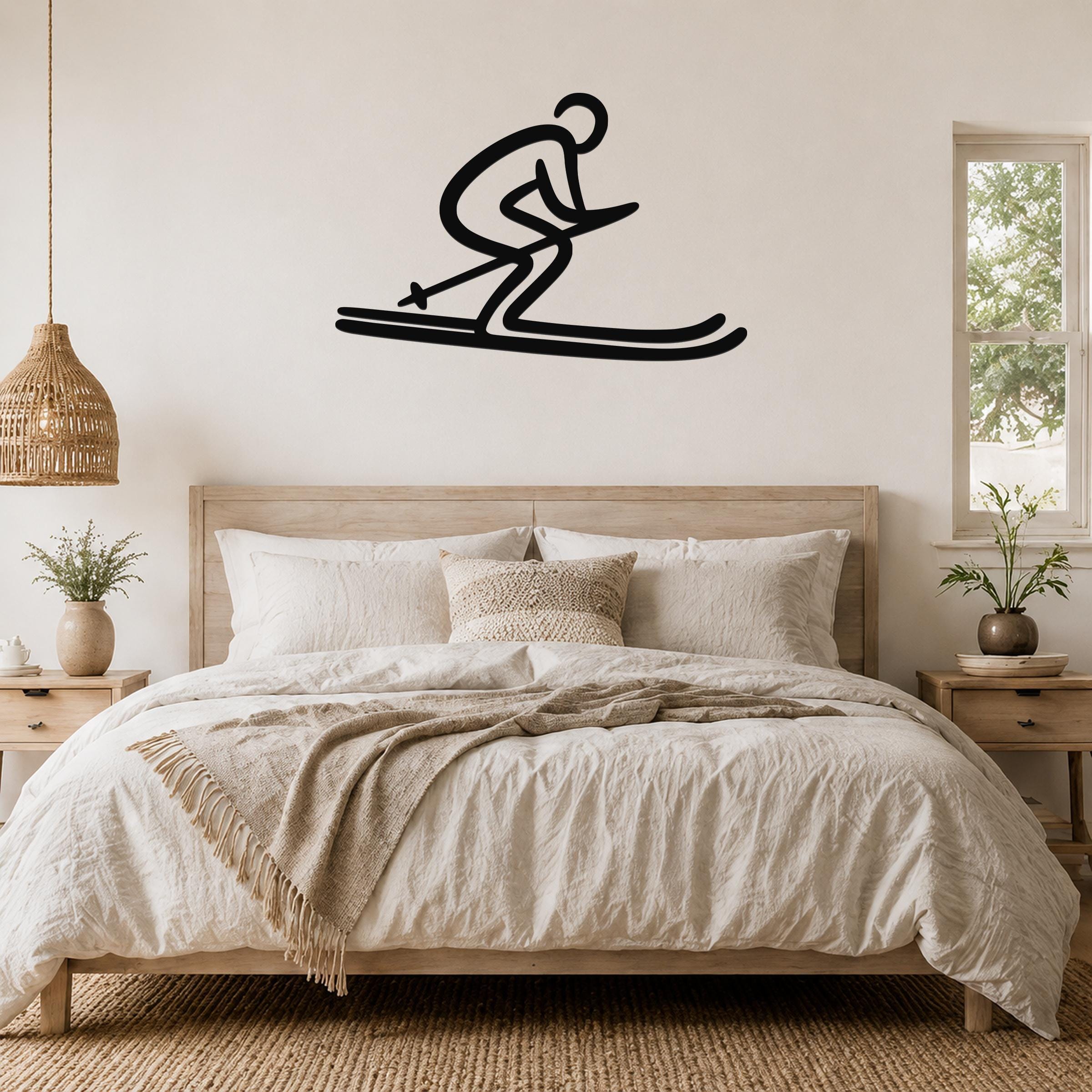 Black metal wall art of a skier silhouette with motion lines, mounted above a bed in a bedroom.