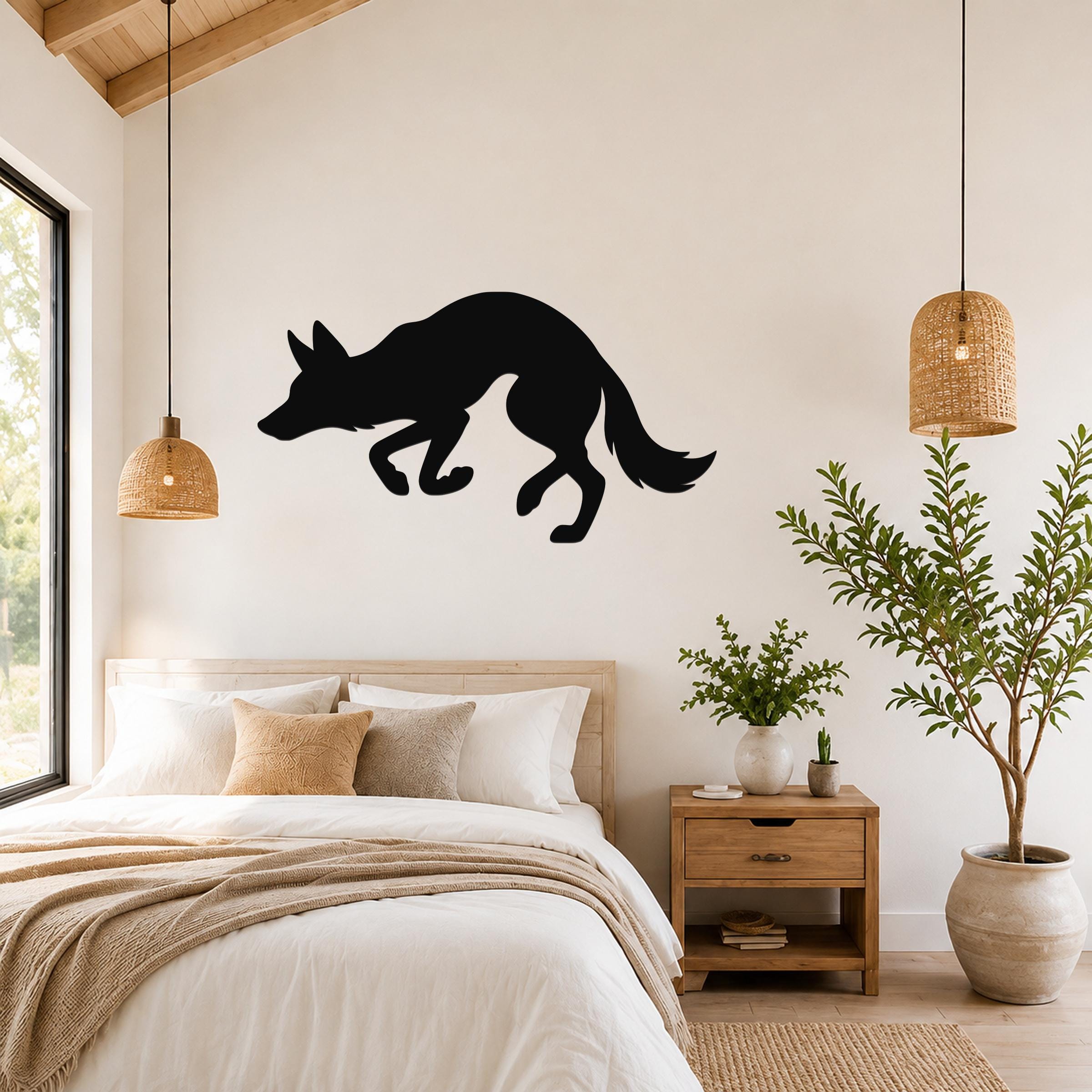 Black metal coyote wall art silhouette mounted above a bed in a bedroom with wooden furniture and woven pendant lights.