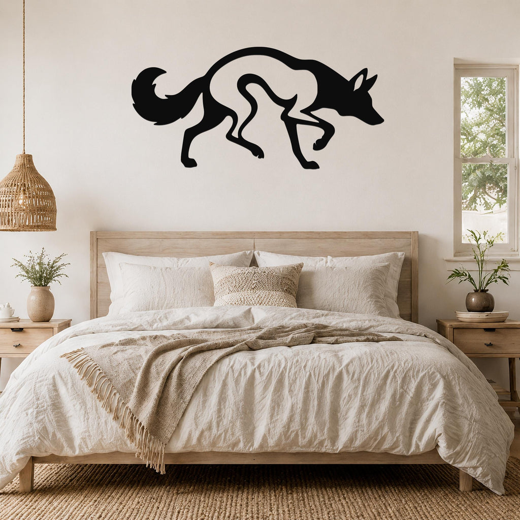 Black metal coyote wall art silhouette with motion-line cutouts, mounted above a bed in a neutral bedroom.