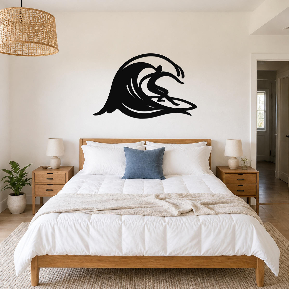 Black metal wall art in a surfer silhouette riding a wave, mounted above a bed in a bedroom.