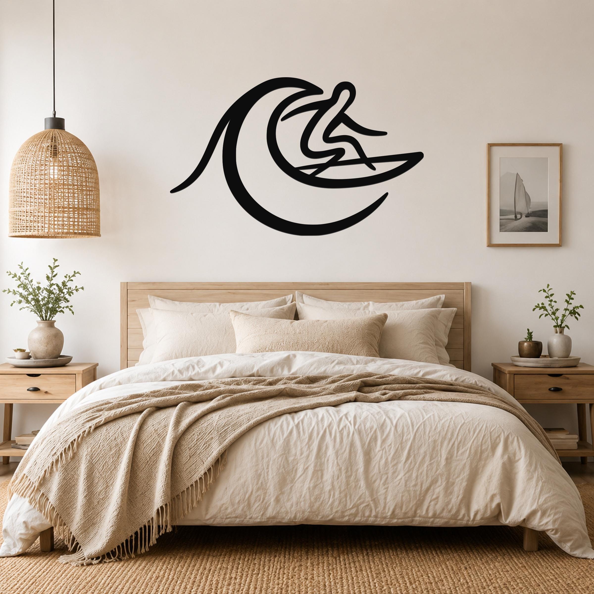 Black metal wall art in a silhouette of a surfer riding a wave, mounted above a bed in a bedroom.