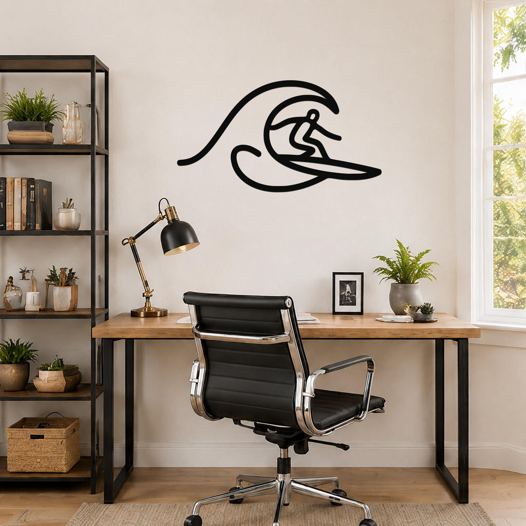 Black metal wall art silhouette of a surfer riding a wave, mounted above a wooden desk in a home office.