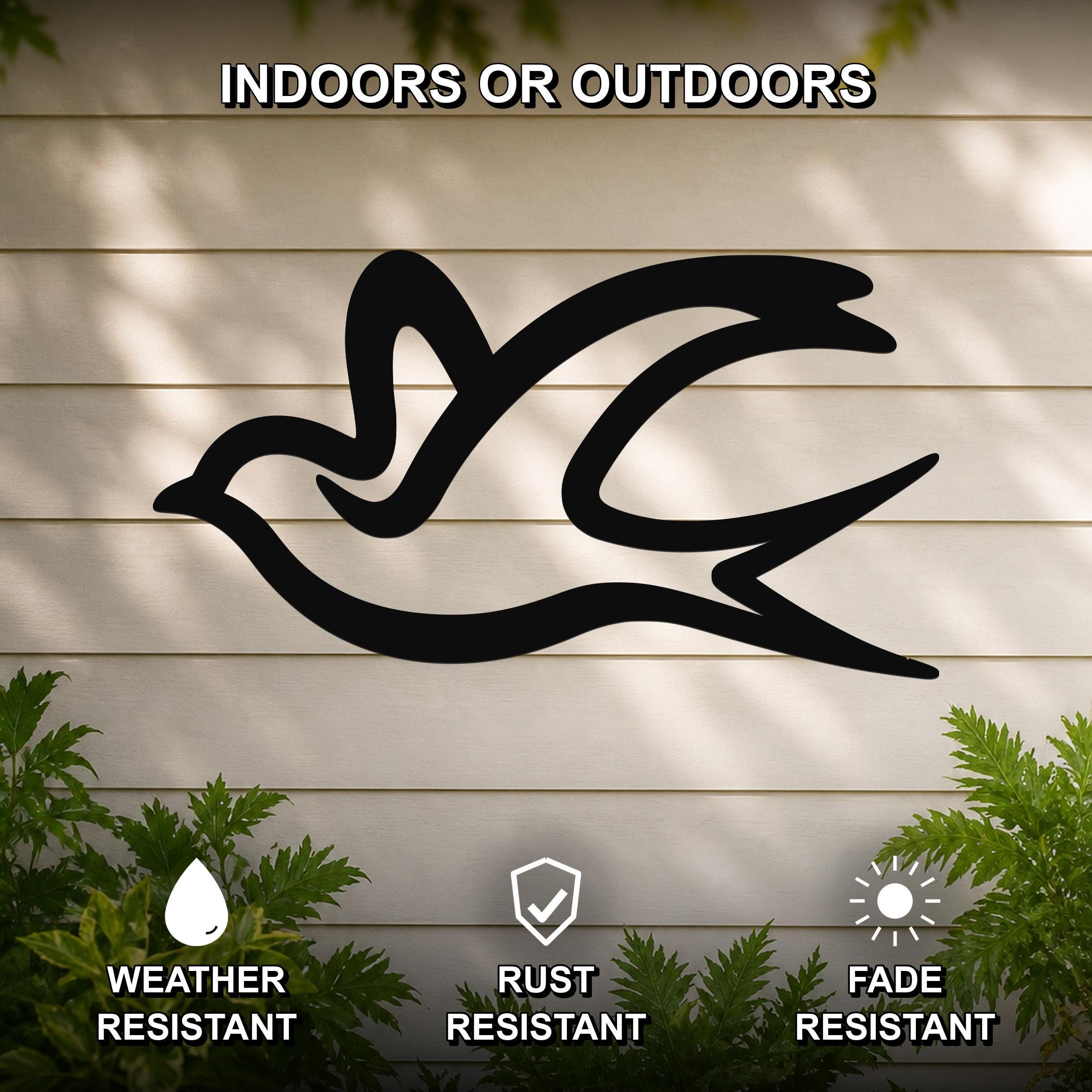 Black metal swallow bird wall art silhouette mounted on a beige outdoor wall, weather resistant, rust resistant, and fade resistant, with green foliage at the base.