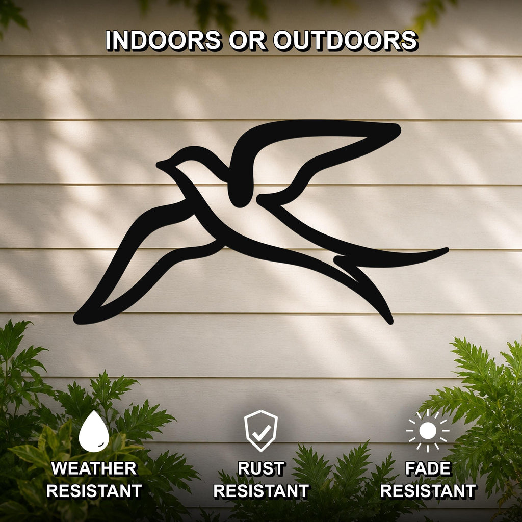 Black metal swallow bird wall art with a graceful silhouette, mounted on a light-colored outdoor wall with greenery, weather resistant, rust resistant, and fade resistant.