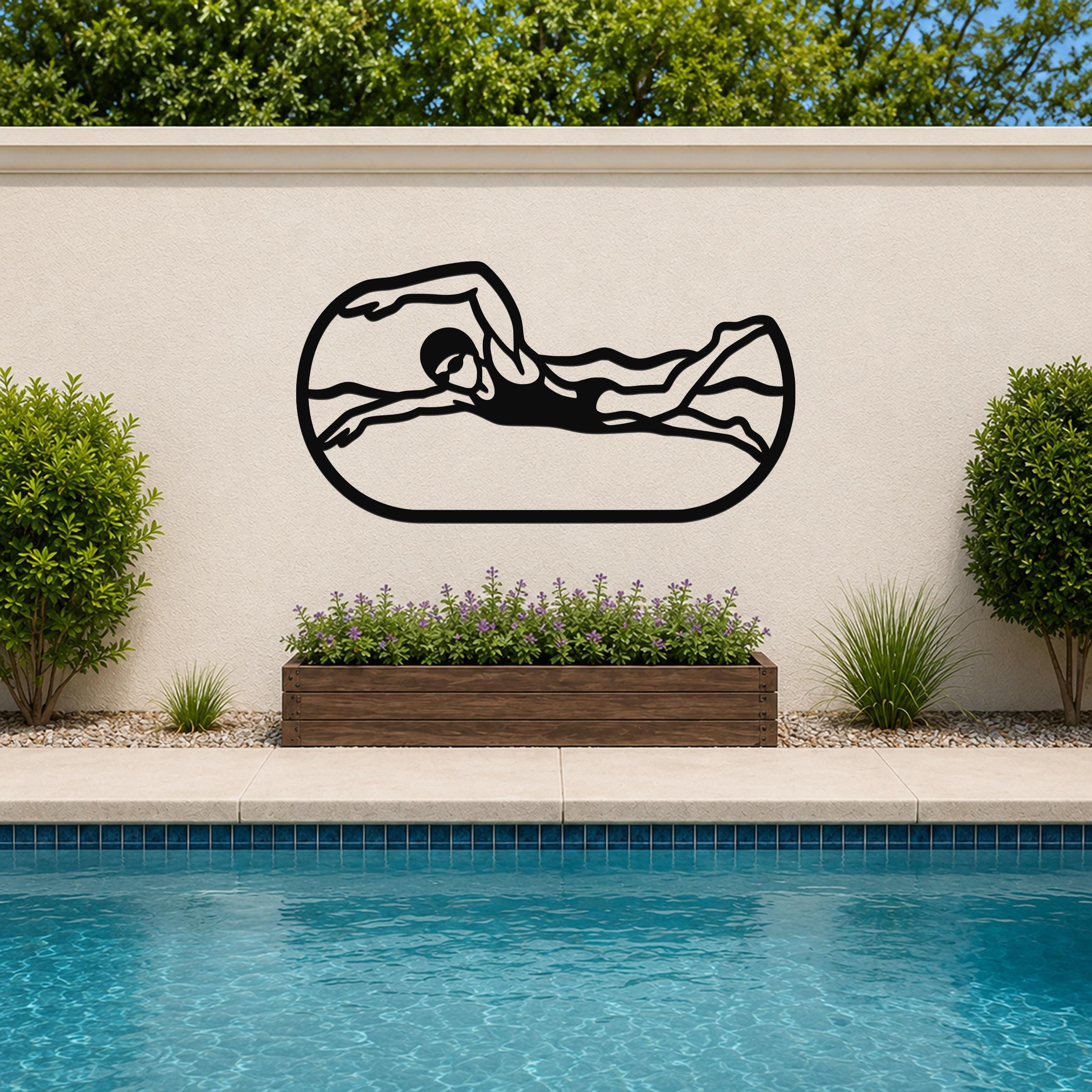 Black metal swimmer wall art with motion-line cutouts, mounted on an outdoor wall above a poolside planter.