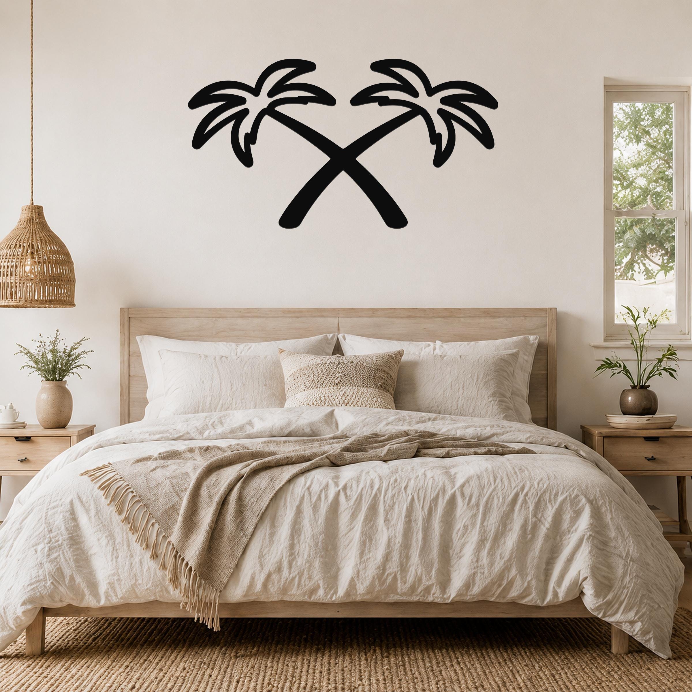 Black metal wall art featuring two crossed palm trees in silhouette, mounted above a wooden bed in a neutral-toned bedroom.