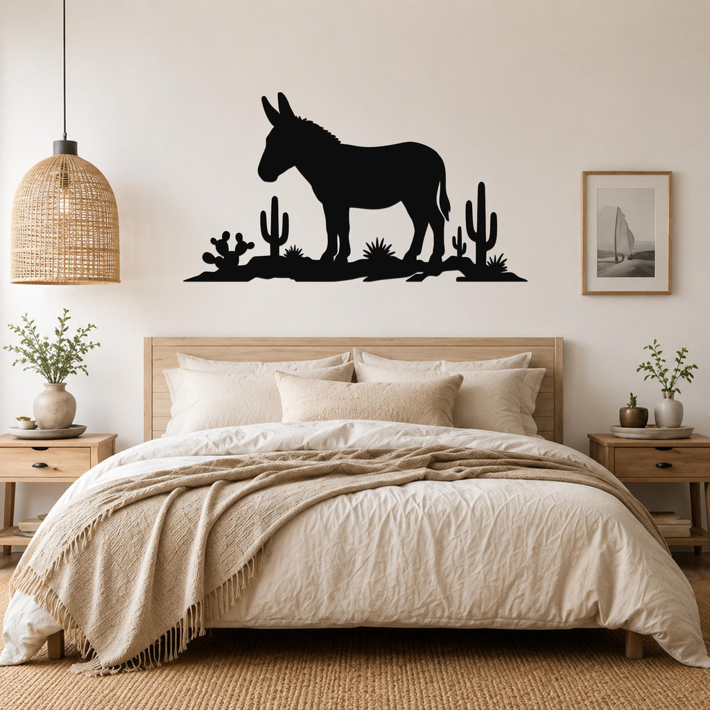 Black metal wall sculpture of a burro silhouette with cacti, mounted above a bed in a neutral bedroom.