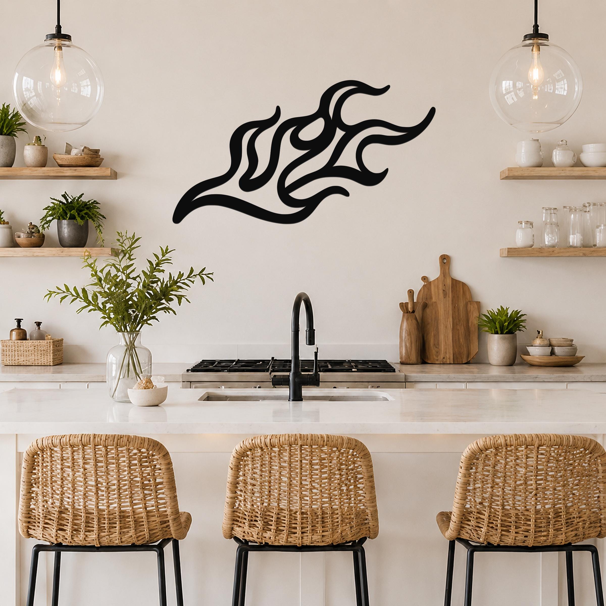 Black metal flame wall art with flowing, abstract cutout design, mounted on a kitchen wall above a counter.