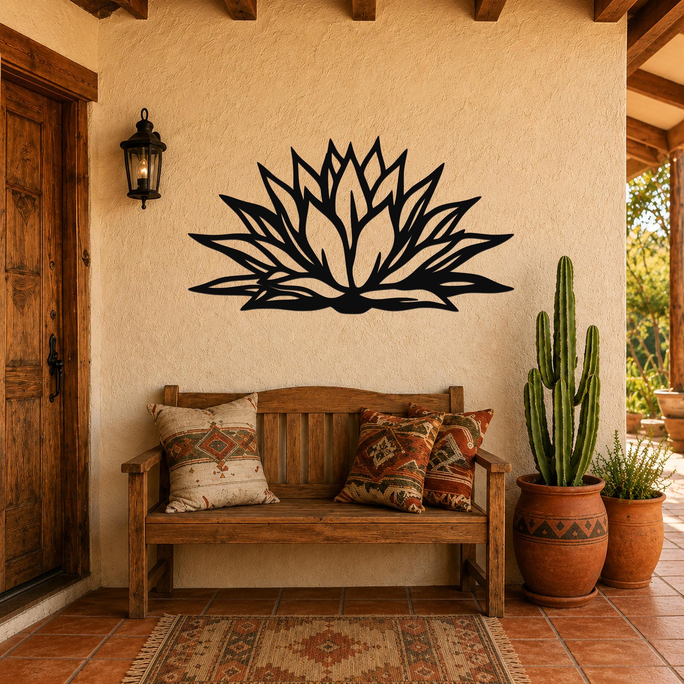 Black metal agave wall art with bold geometric cutouts, mounted on a stucco wall above a wooden bench in a patio entryway.