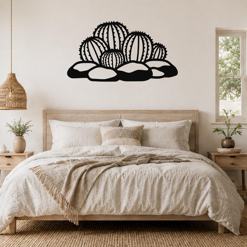 Black metal barrel cactus wall art with spines and rocks cutouts, mounted above a bed in a neutral bedroom.