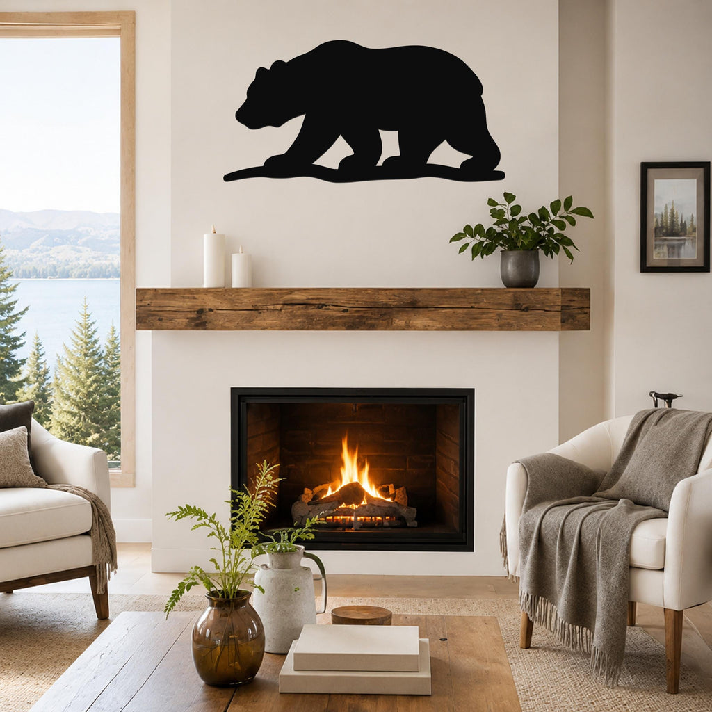 Black metal bear silhouette wall art mounted above a fireplace in a living room with a lake view.