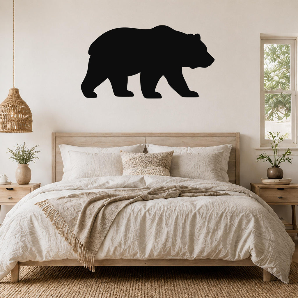 Black metal bear silhouette wall art mounted above a wooden bed in a neutral bedroom.
